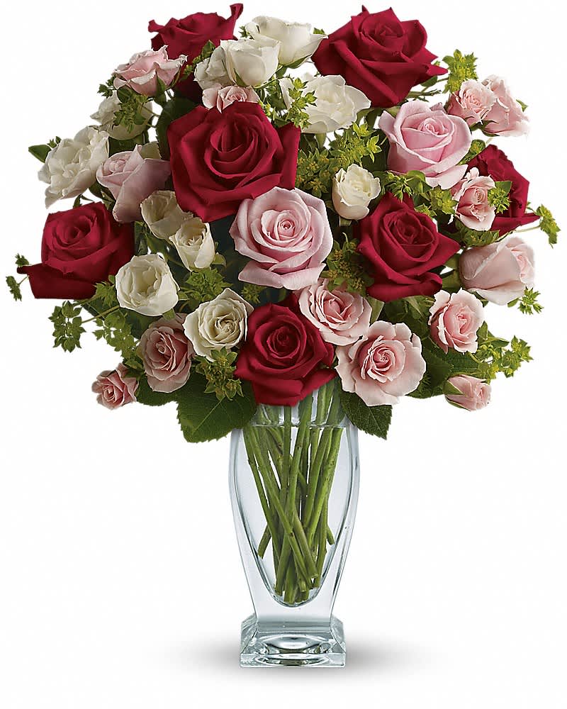 Tall glass vase of red, pink, and white roses with spray roses in a rounded arrangement