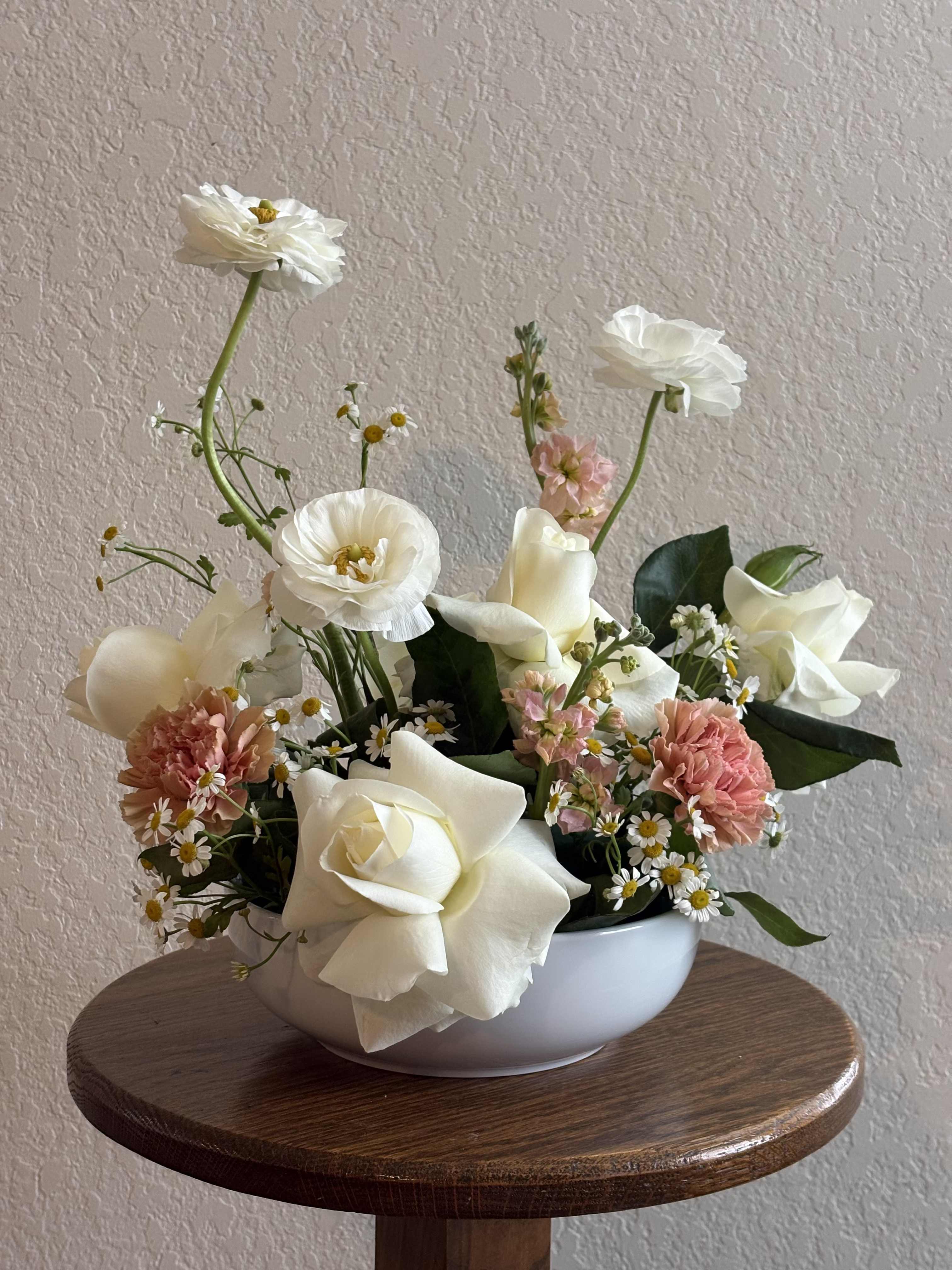 White roses and pink carnations in a white bowl vase