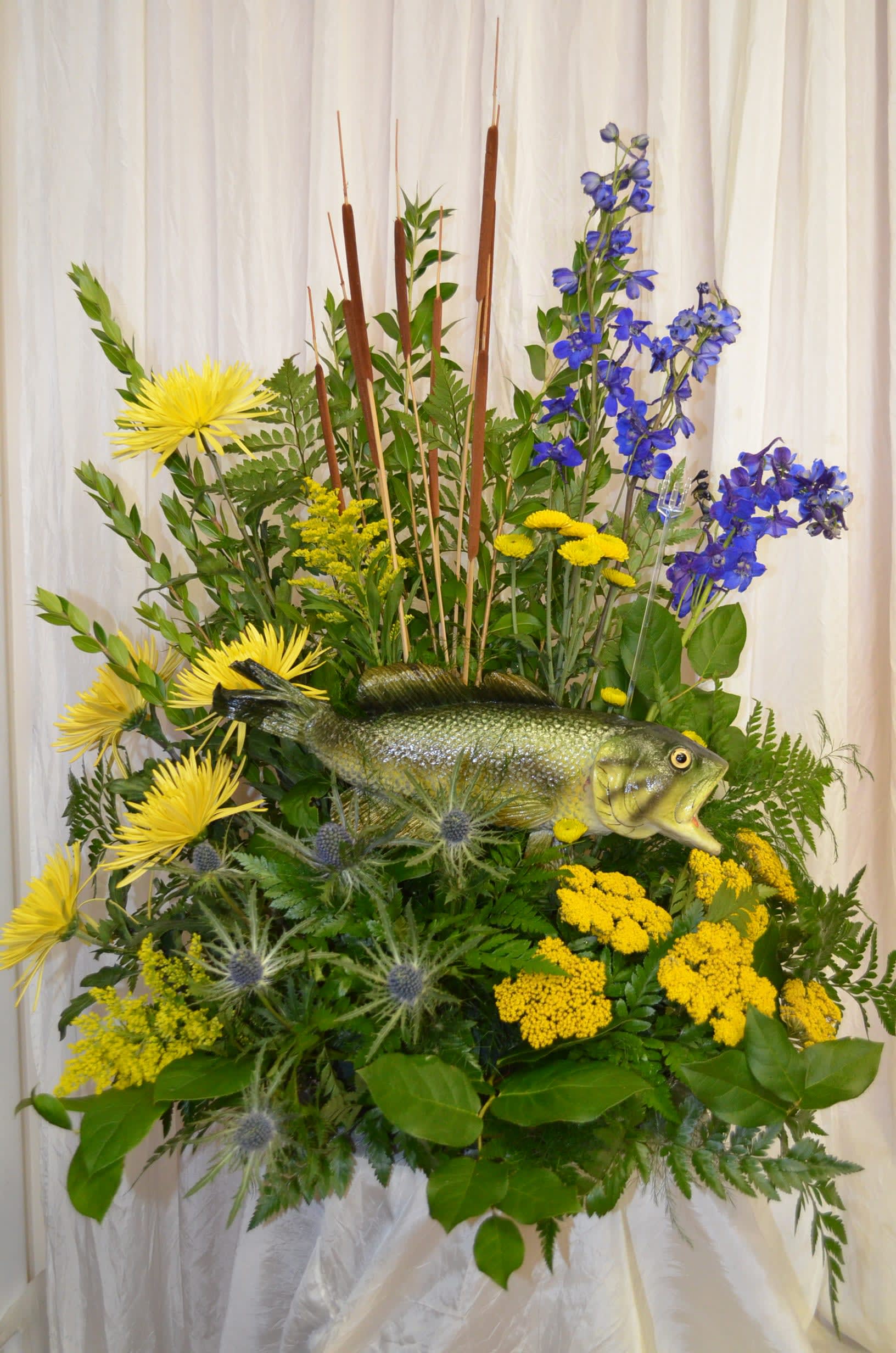 Floral arrangement with a fish centerpiece in yellow, blue, and green