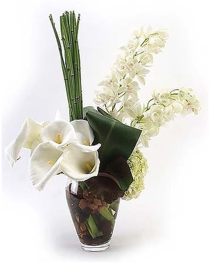 Tall modern arrangement of white calla lilies and orchids with vertical green stalks in a clear glass vase