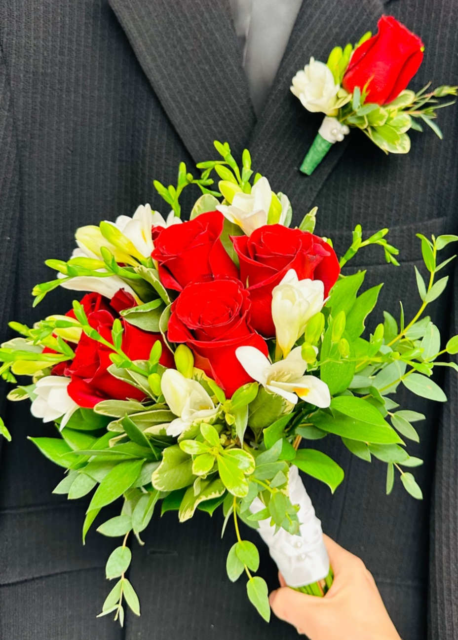 Red roses and white flowers in a hand-tied bouquet with green foliage