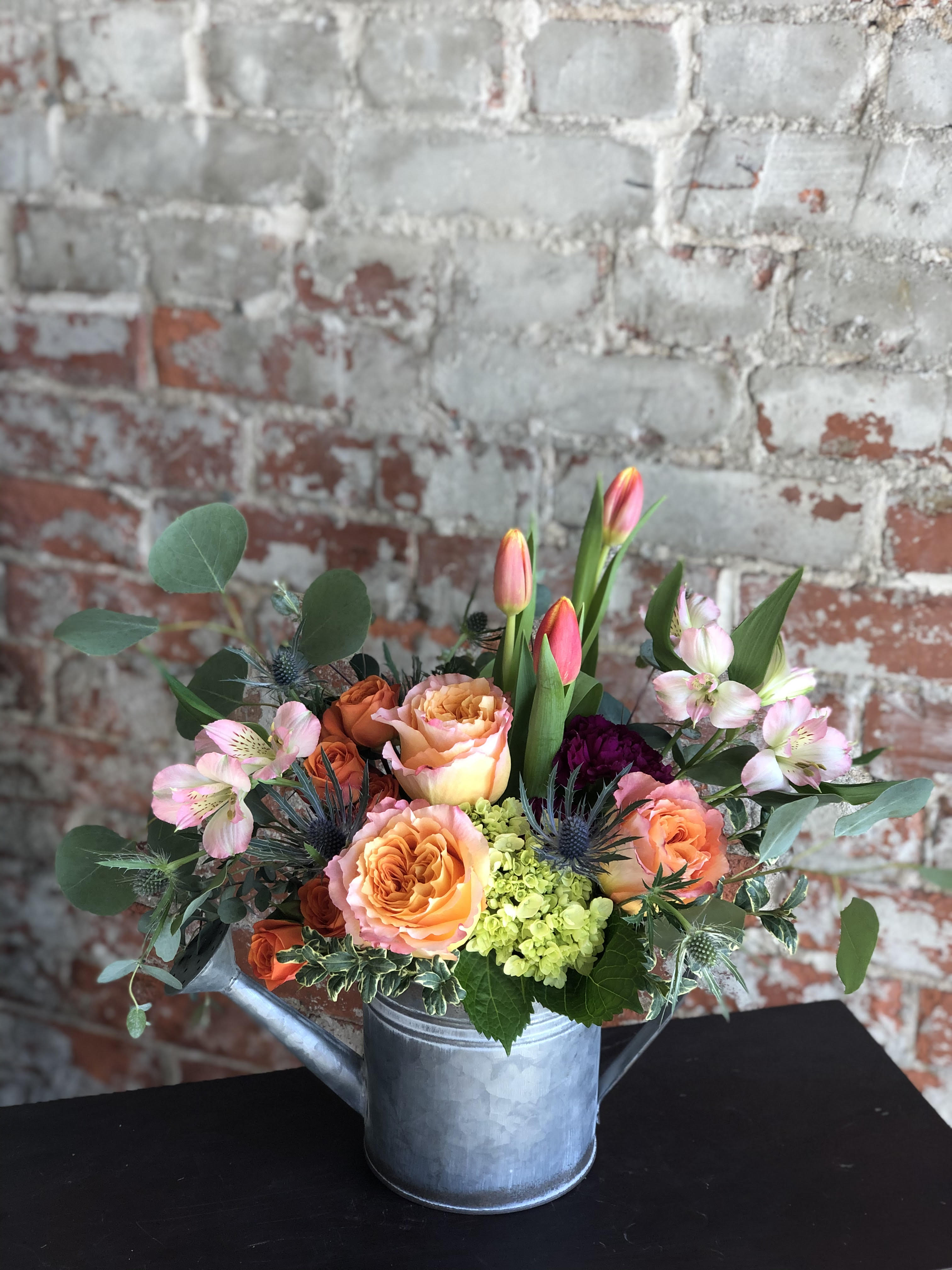Mixed bouquet in a metal watering can with peach roses and pink tulips