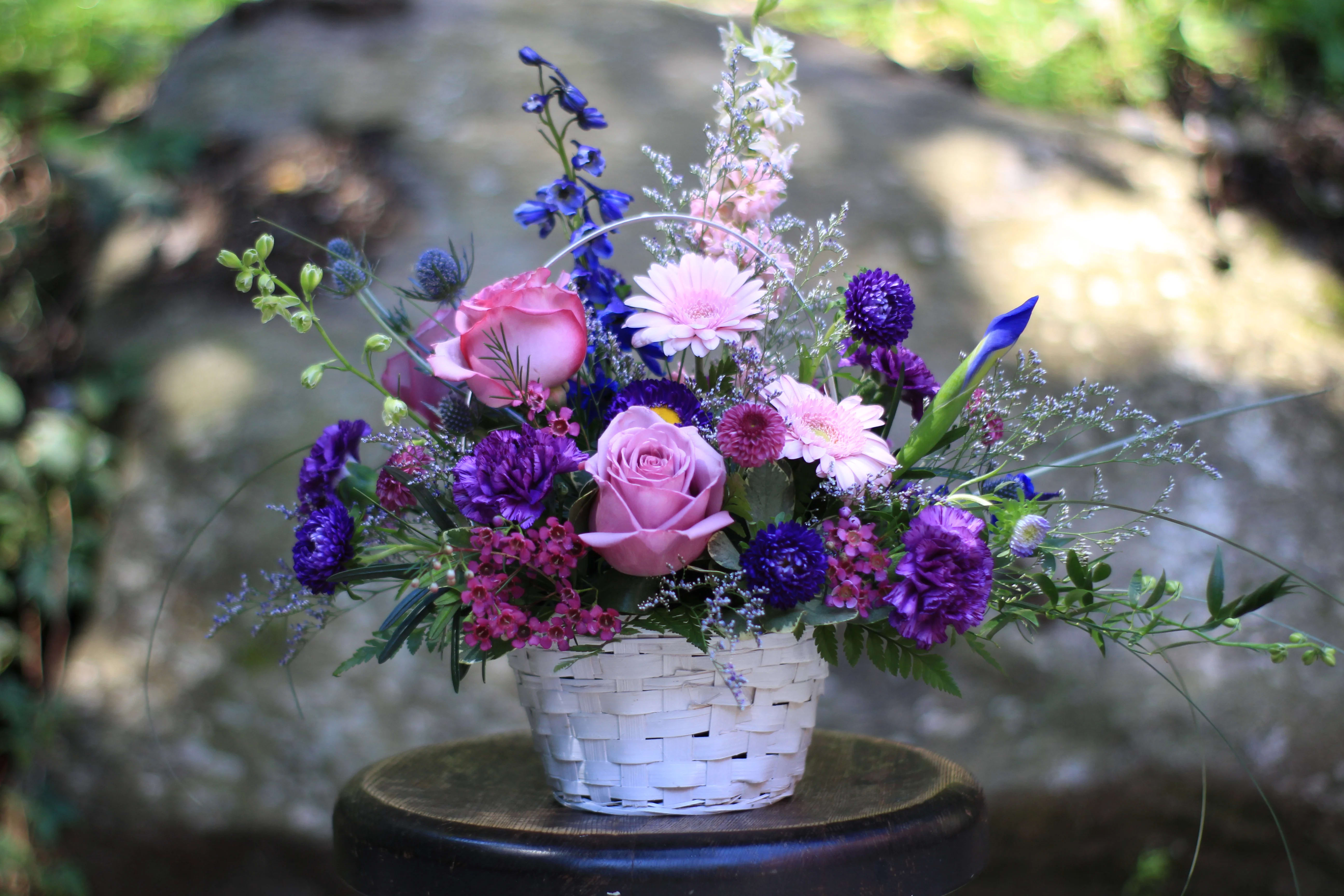 Basket of Blooms By Lucille's - Country garden flowers arranged in a lovely basket. Pink, purple and blue flowers make for a beautiful combination for any occasion.