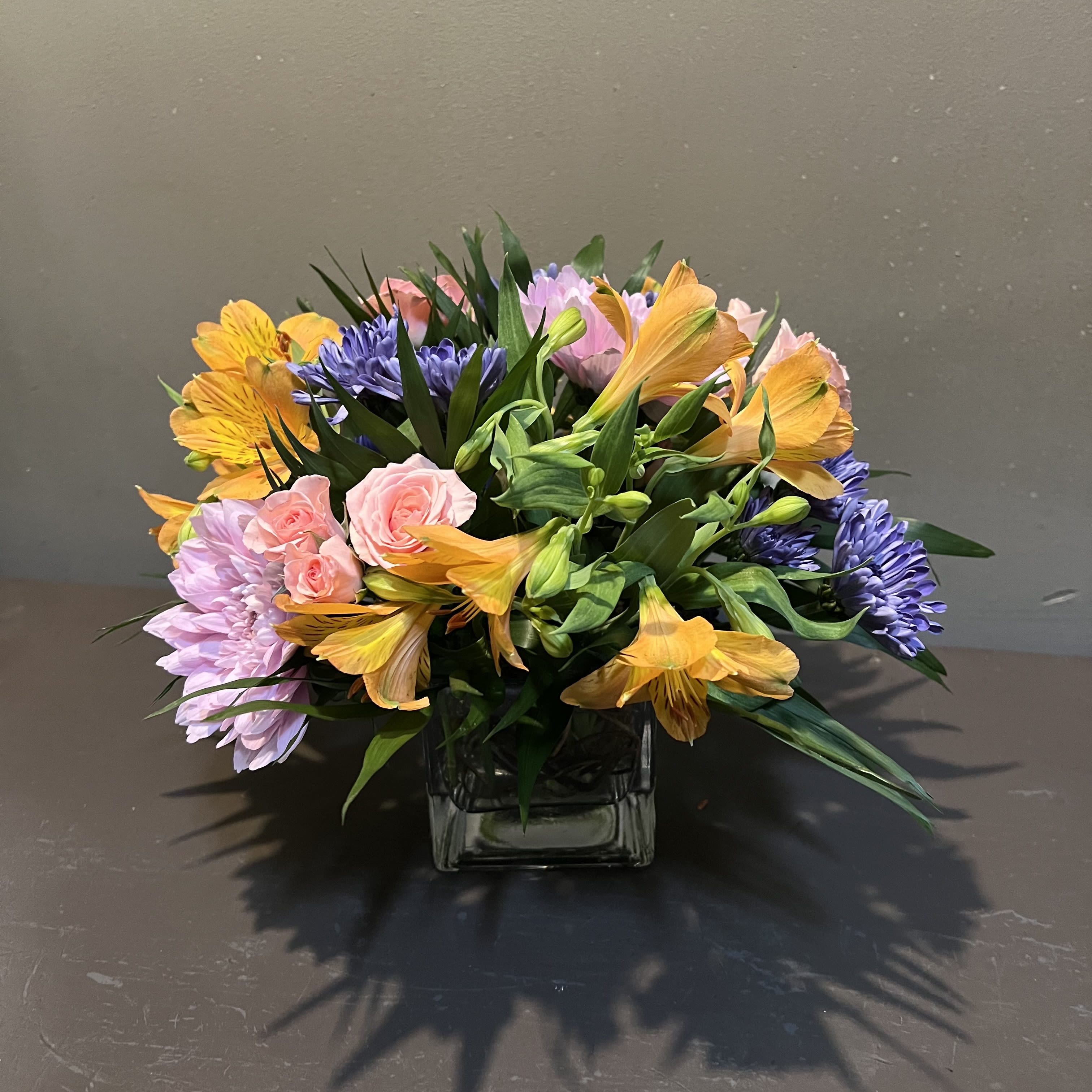 Punch of Color - Lush colorful tones in a low vase - perfect for a coffee table or side table.  Measures approx. 11"Tx11"W.
