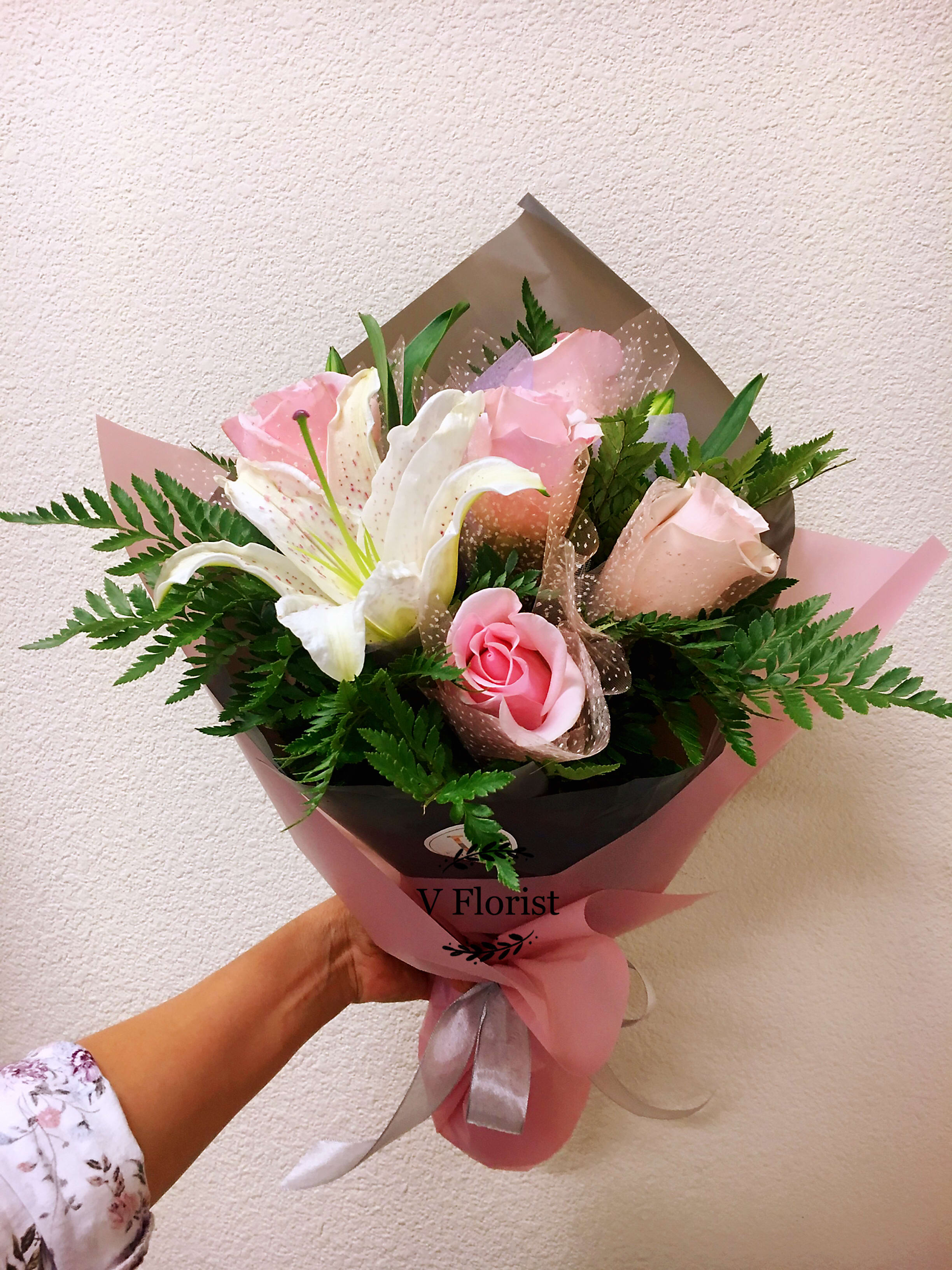 Pink roses and white lilies in pink and brown wrapping