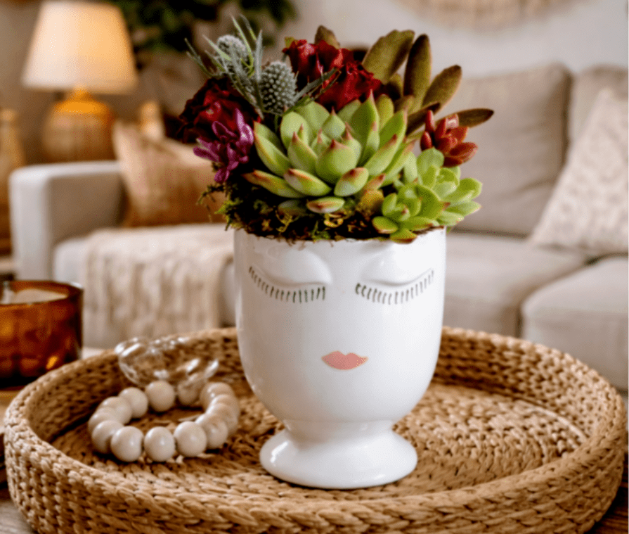 Brea - The Brea arrangement is a modern boho statement piece designed to bring effortless California style into any space. Artfully composed with lush mixed succulents, textural greenery, and rich seasonal accents, this arrangement is styled in a chic ceramic face vessel that adds personality and charm to your home or office décor.  Inspired by relaxed family homes and laid-back bohemian interiors, Brea features sculptural succulents layered with earthy tones of soft green, deep burgundy, and warm natural textures. Its low-maintenance design makes it perfect for coffee tables, entry consoles, shelves, or gifting for housewarmings, celebrations, or just because.  This long-lasting succulent arrangement blends organic beauty with contemporary design, making it an ideal accent for modern boho, coastal, eclectic, or farmhouse-inspired interiors.  Details:  Premium mixed succulents and botanical accents  Styled in a modern ceramic face vase  Long-lasting, low-maintenance design  Perfect for coffee tables, living rooms, offices, and gifting  Each arrangement is handcrafted and unique  Perfect for: Boho home décor, modern family homes, coffee table styling, housewarming gifts, California-inspired interiors, and succulent lovers.  Care: Place in bright, indirect light. Water sparingly and enjoy for months to come.