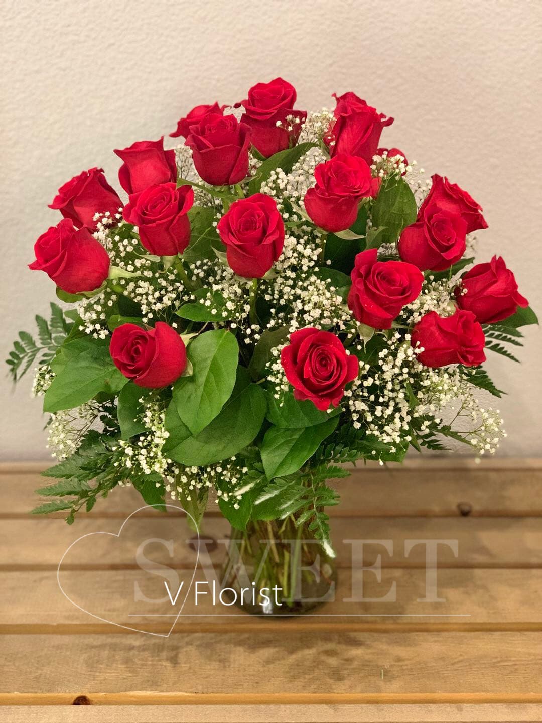 Bouquet of red roses with white baby's breath in a clear glass vase