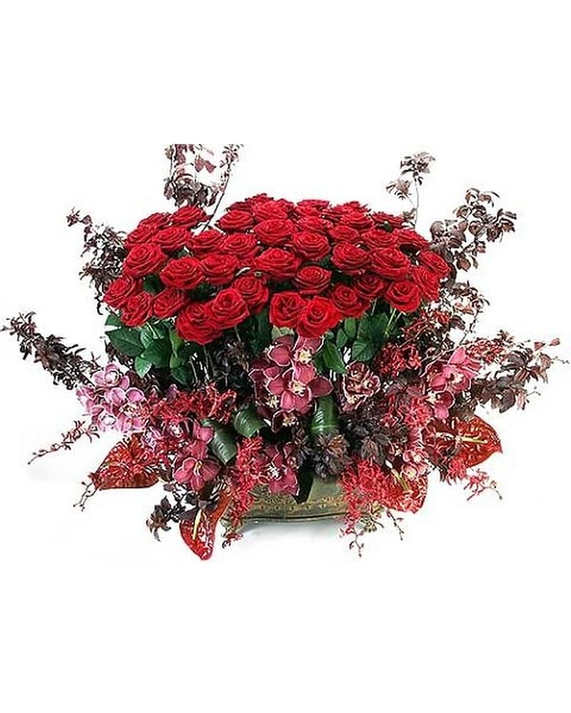 Large arrangement of red roses with pink orchids and red accents in a low gold bowl