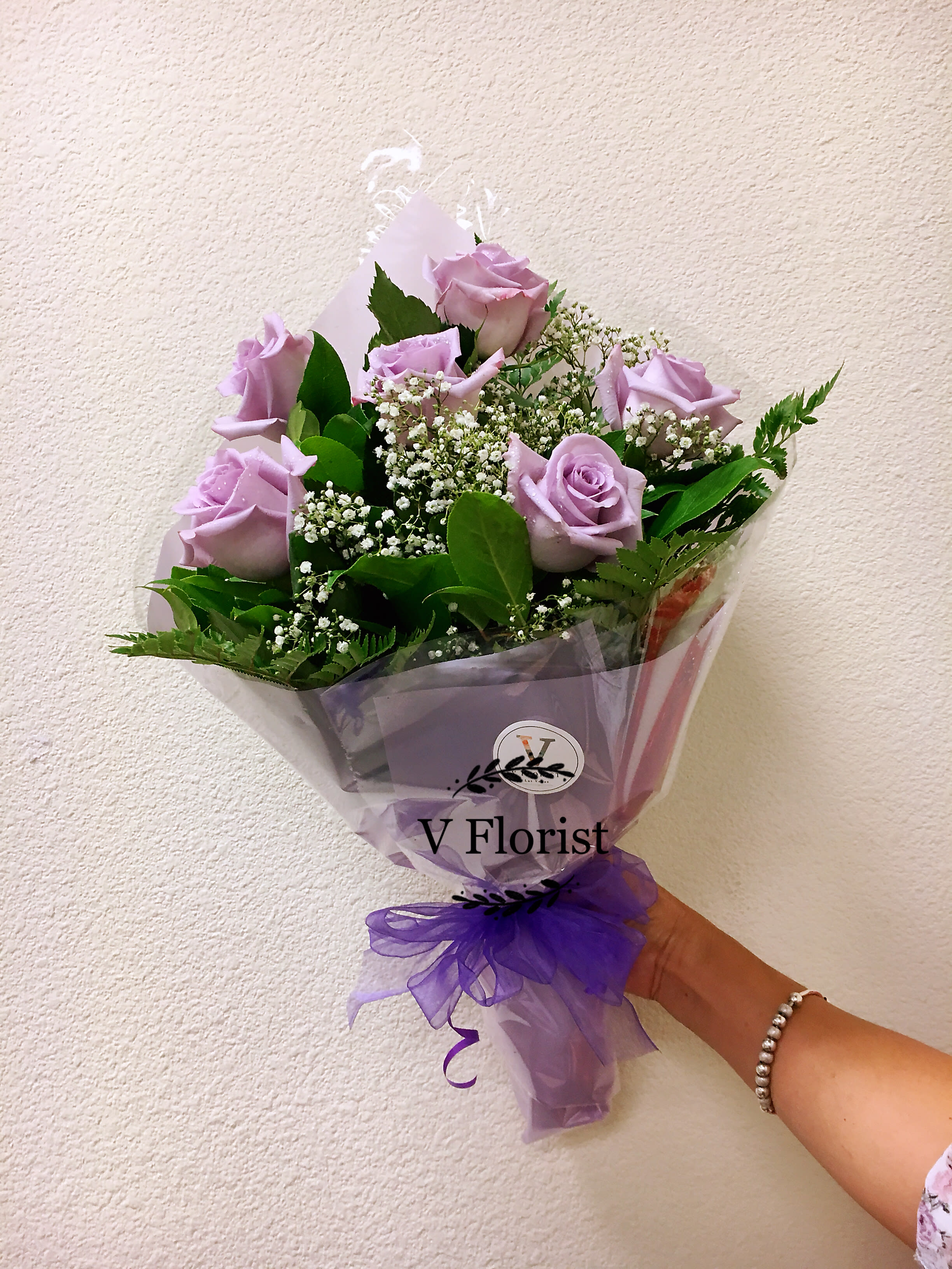 Lavender rose bouquet wrapped in purple paper with a ribbon