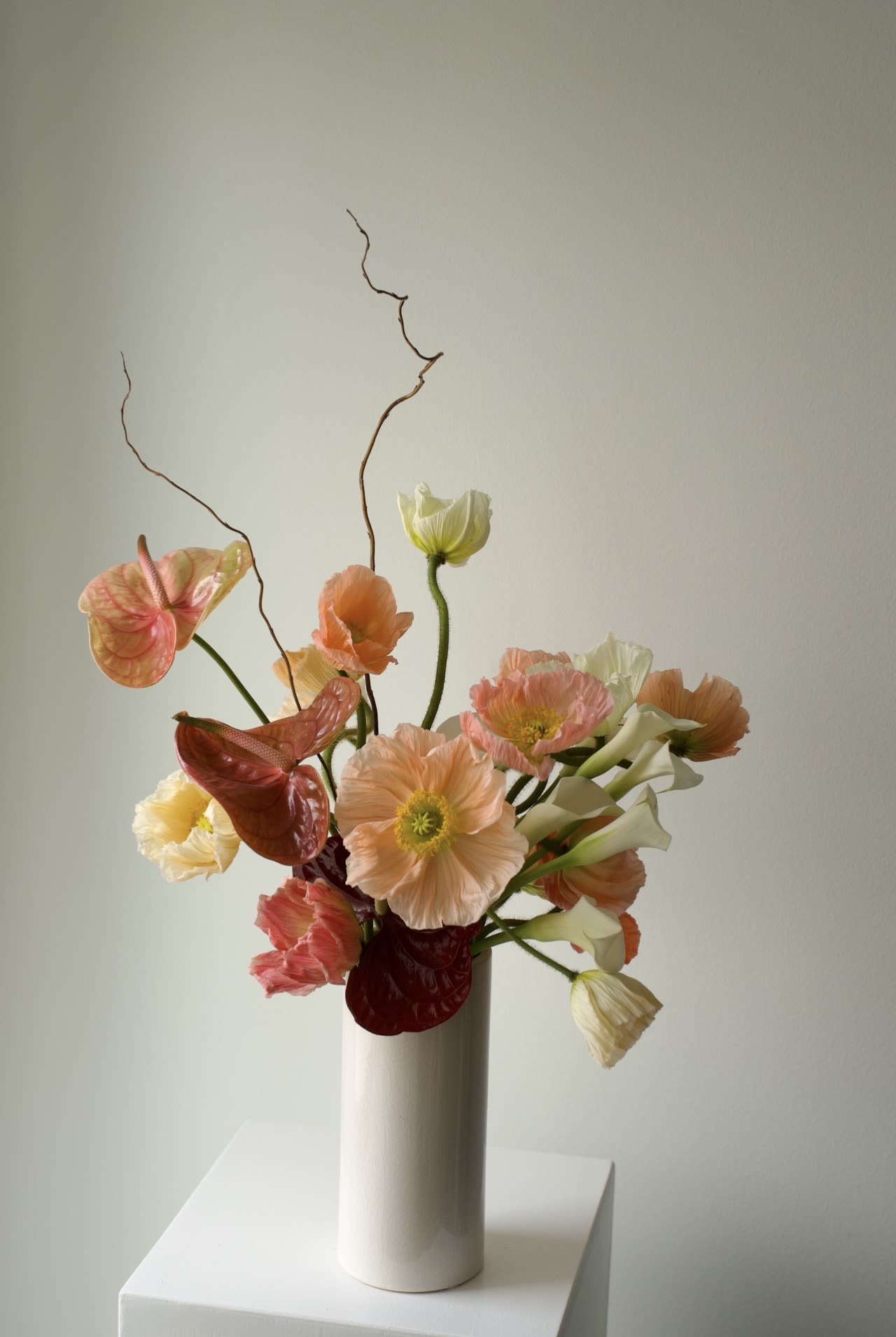 Coral Air - An airy, sculptural spring arrangement with a refined, modern feel.  Featuring poppies, calla lilies, anthurium, and seasonal blooms in soft coral, peach, and cream tones.  Light, expressive, and naturally asymmetrical — it feels like a living composition in motion. 