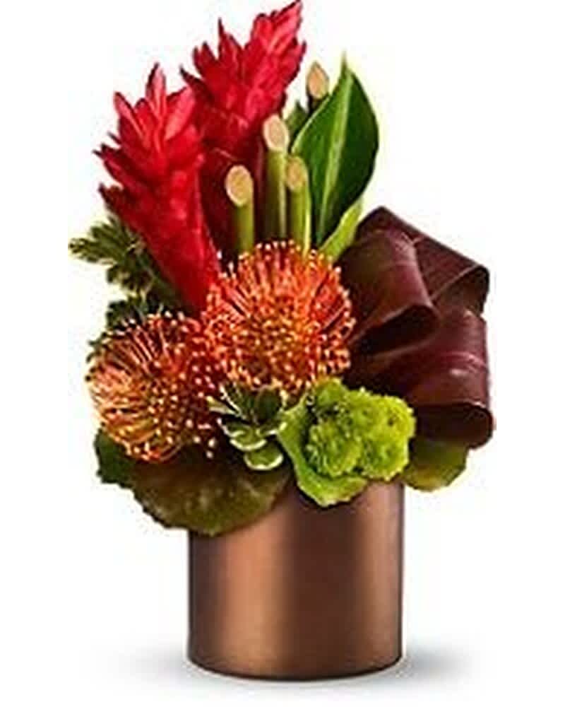 Tropical arrangement with red and orange flowers, green accents, and curled leaves in a bronze cylinder vase