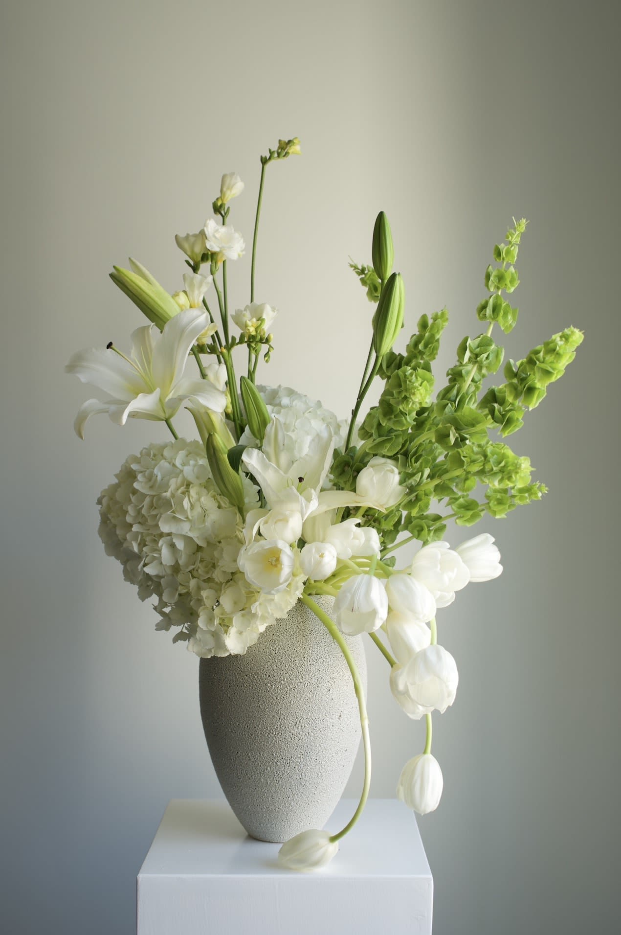 After Rain - A fresh, light-filled arrangement in crisp white and vibrant green tones.  Featuring tulips, hydrangea, lilies, and seasonal blooms, it feels clean, airy, and effortlessly calm.  Soft movement and natural lines create a sense of quiet clarity — like a breath of fresh spring air. 