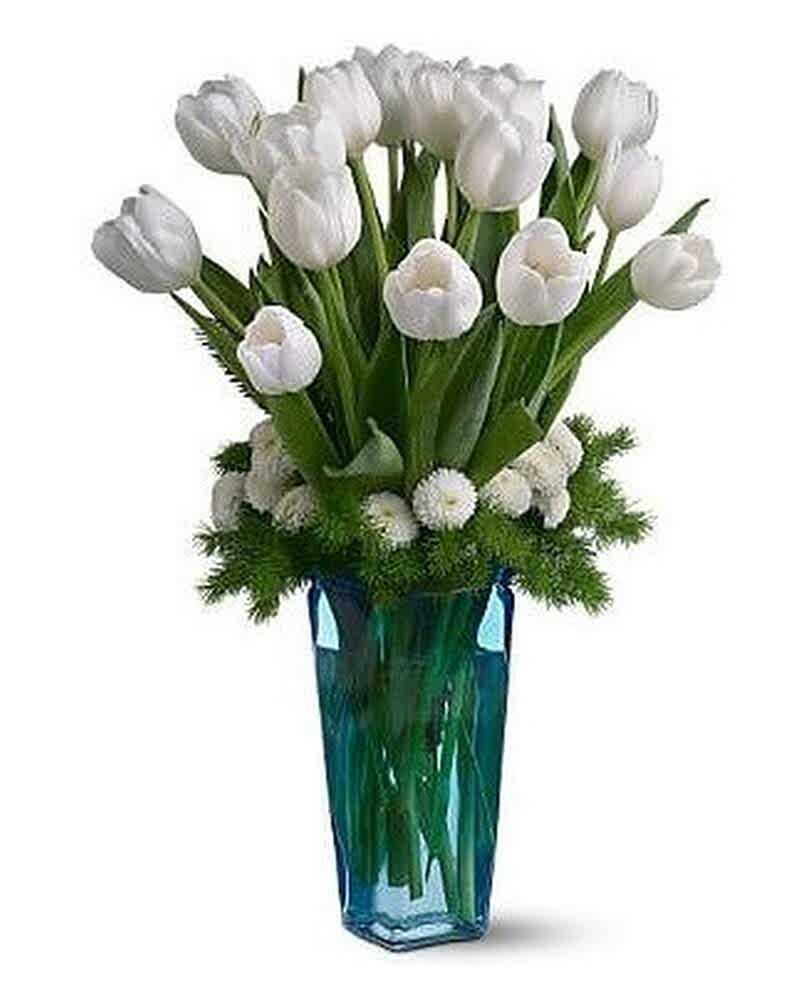 Tall arrangement of white tulips and small white blooms in a blue glass vase