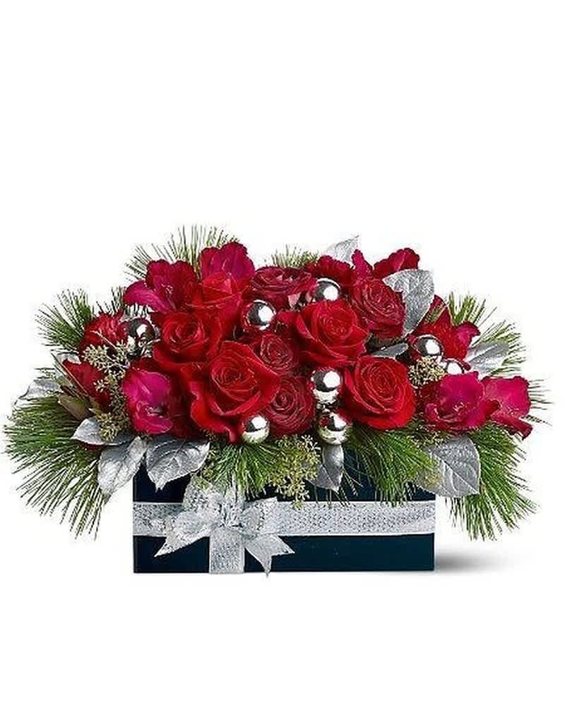 Low arrangement of red roses with pine, silver ornaments, and ribbon in a dark rectangular box
