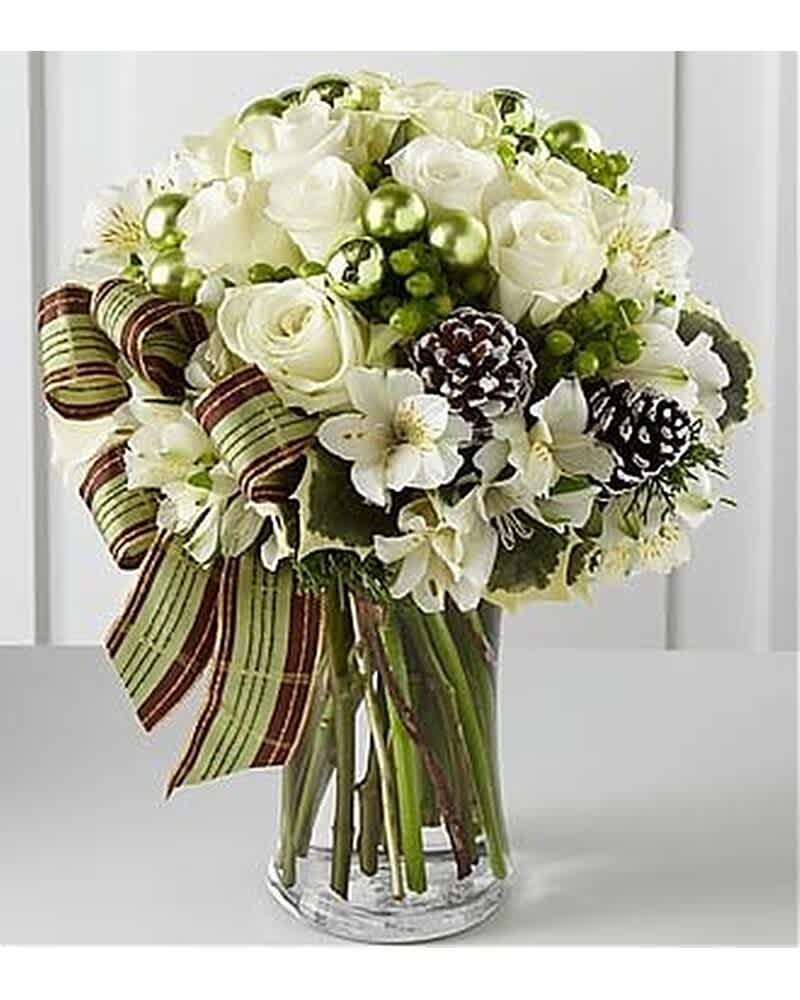 Bouquet of white roses and lilies with pinecones and green ornaments in a clear glass vase