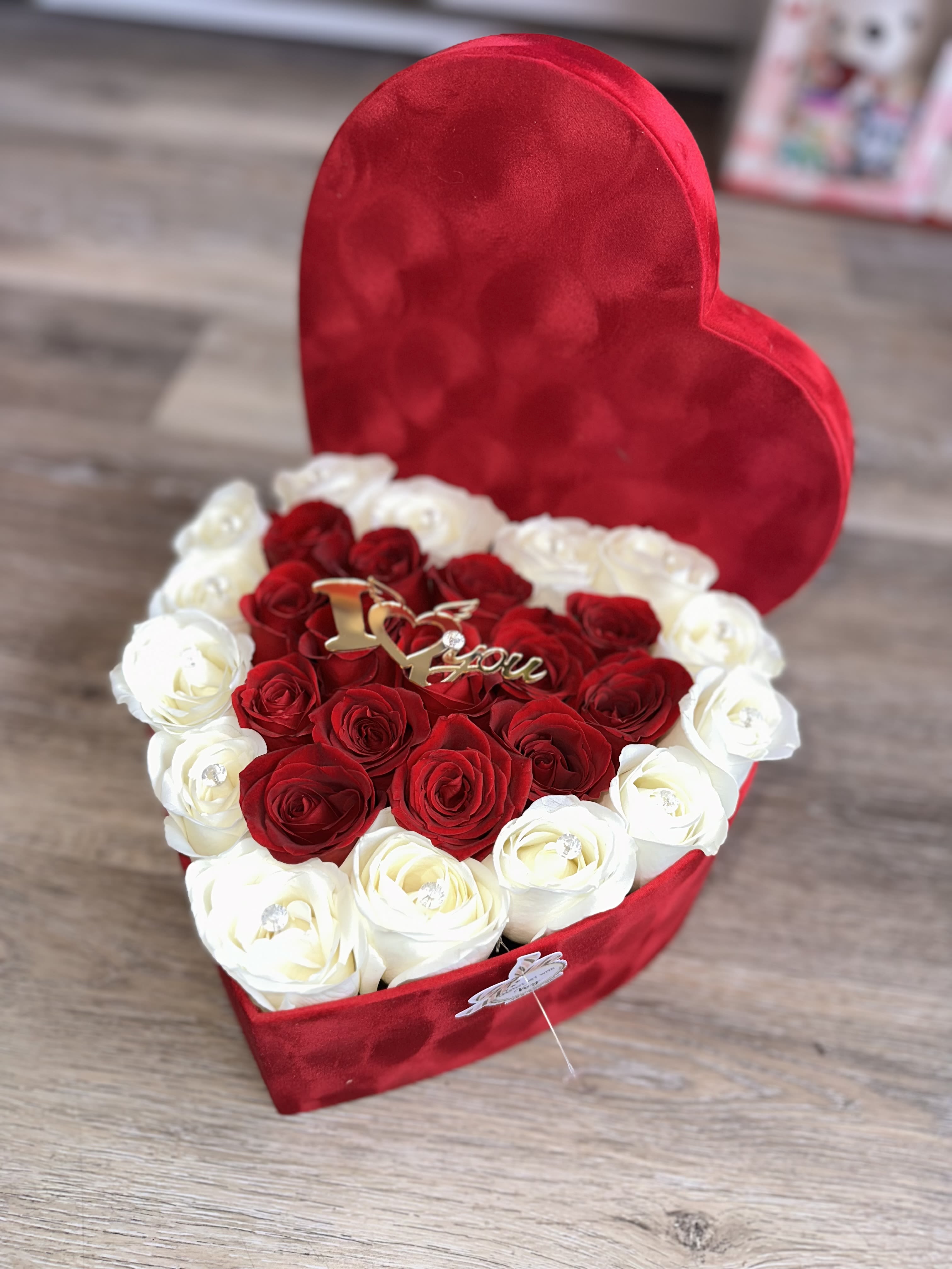 Heart-shaped red box filled with red and white roses