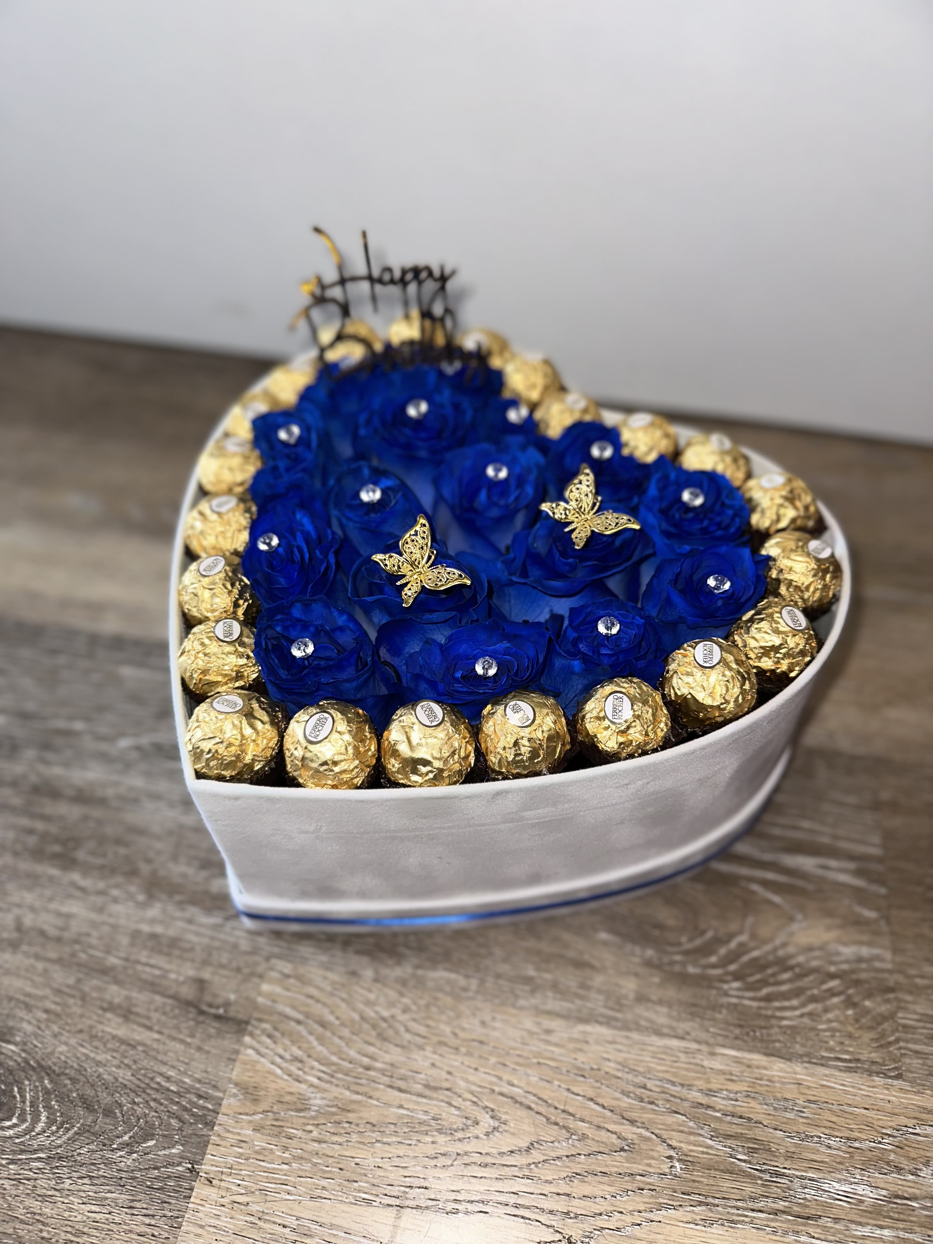 Heart-shaped box of blue roses with gold-wrapped chocolates