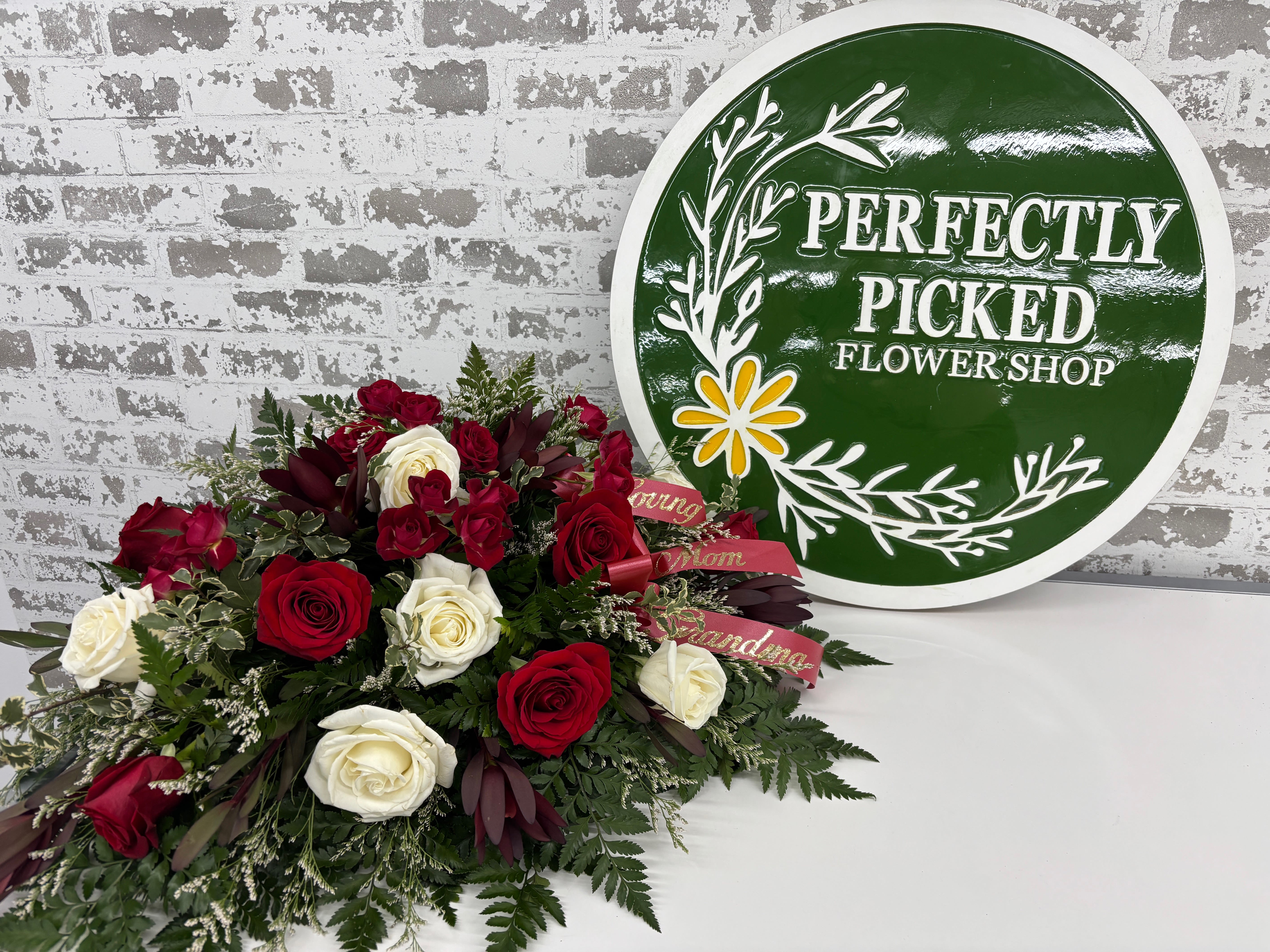 Remember Me (Red) - Nestled within a bed of lush greenery, each bloom reflects the spirit of the one being honored. Thoughtfully designed, this elegant piece brings comfort to those gathered in the spirit of the one being honored.