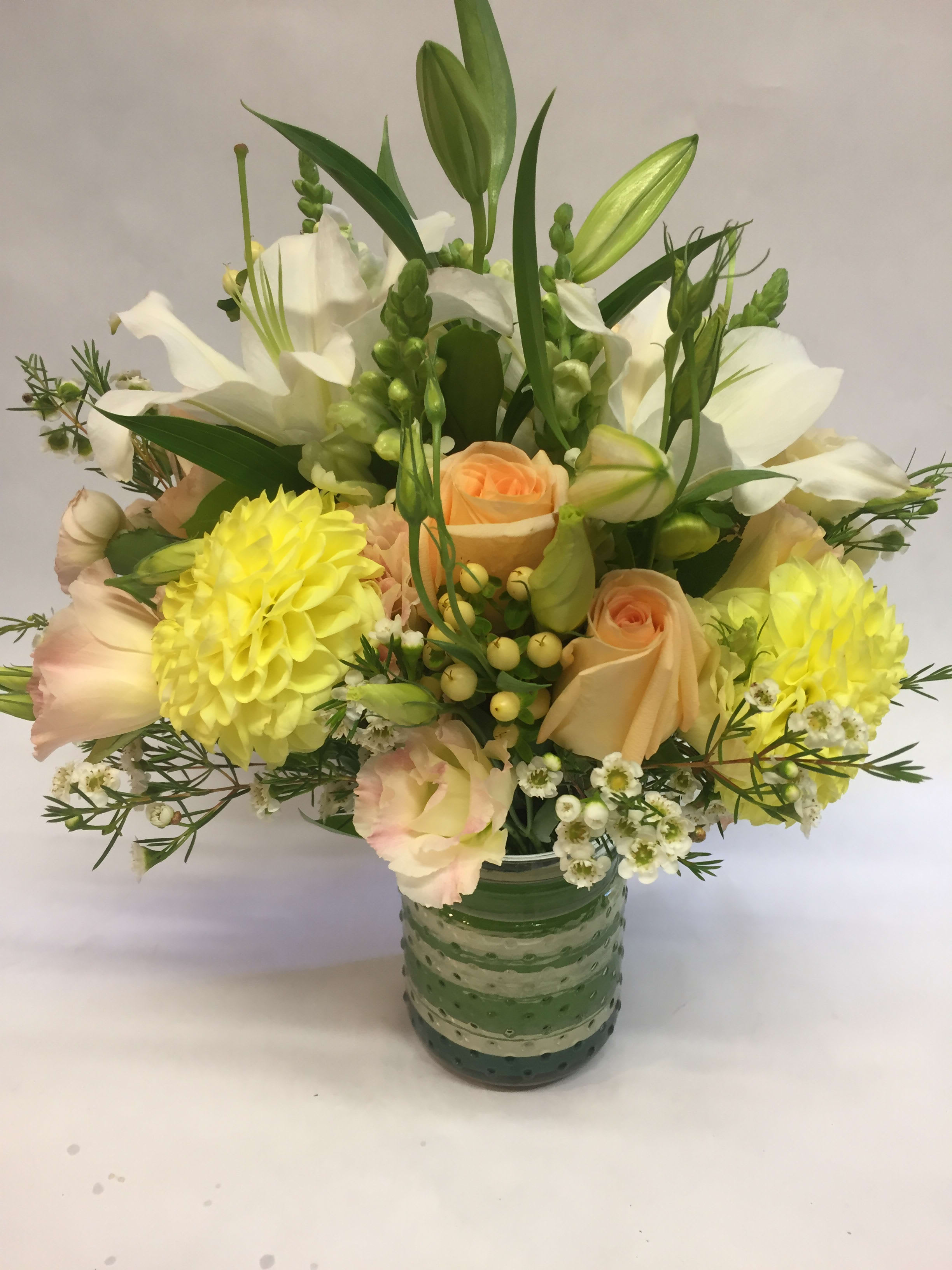 Mixed bouquet of white and peach flowers in a green glass vase