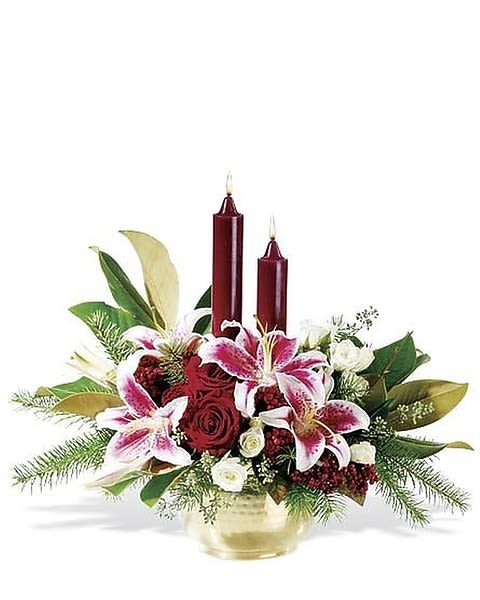 Illumination Lilies - Illuminate the night with a jubilant Christmas centerpiece of glorious mixed blossoms in a shining brass bowl. Our spectacular holiday arrangement features stargazer lilies and magnolia leaves mingled with classic red roses, glossy red berries and evergreens. Two red candles create a glowing display. 