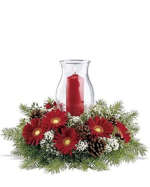 Illumination Centerpiece - A circle of cheerful red gerberas – surrounding a tall glass hurricane with a red pillar candle inside – will make this a very merry Christmas indeed! Frothy white gysophila and real pinecones add interest to this festive holiday centerpiece.