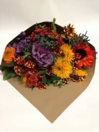 Mixed bouquet with purple, yellow, orange, and red flowers in brown paper