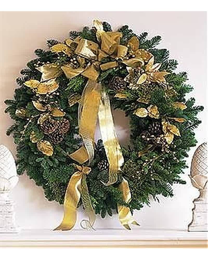Evergreen wreath with gold ribbon, pinecones, and gold accents hanging above a mantel.