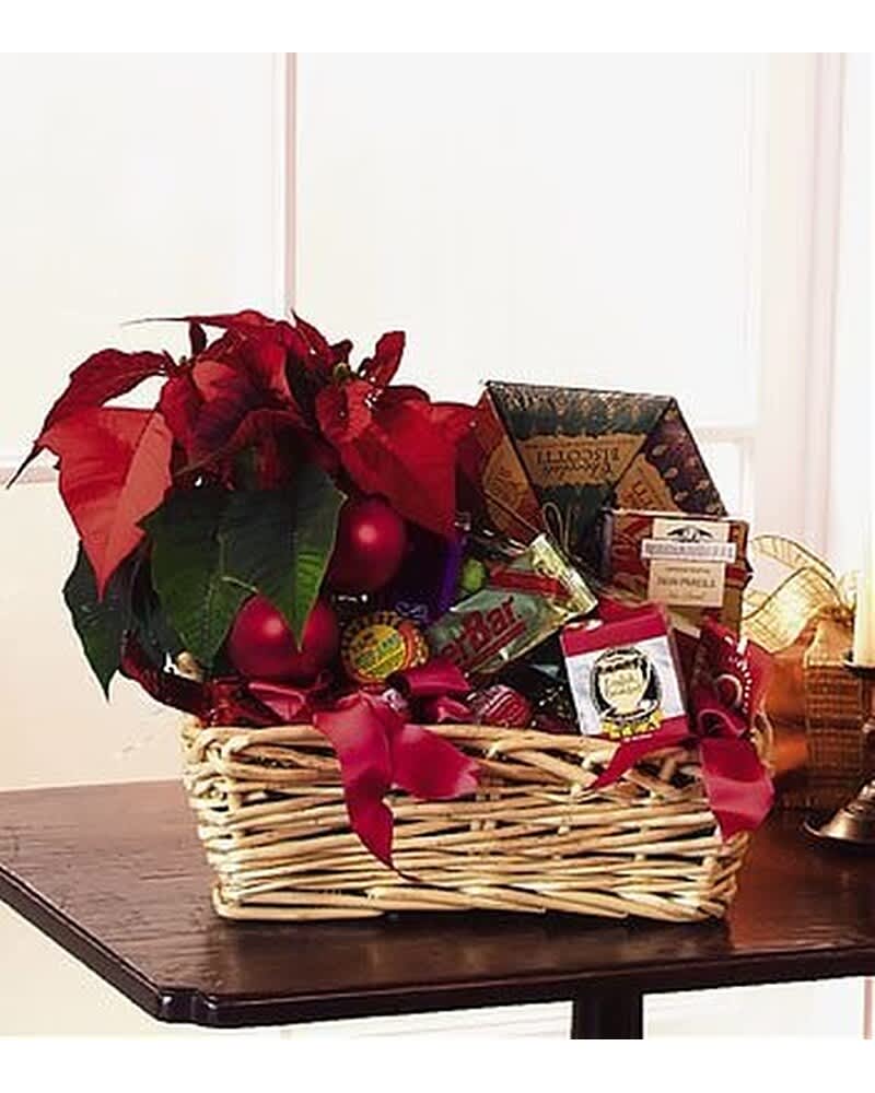 Wicker gift basket with red poinsettia plant, red ornaments, and assorted packaged snacks and treats