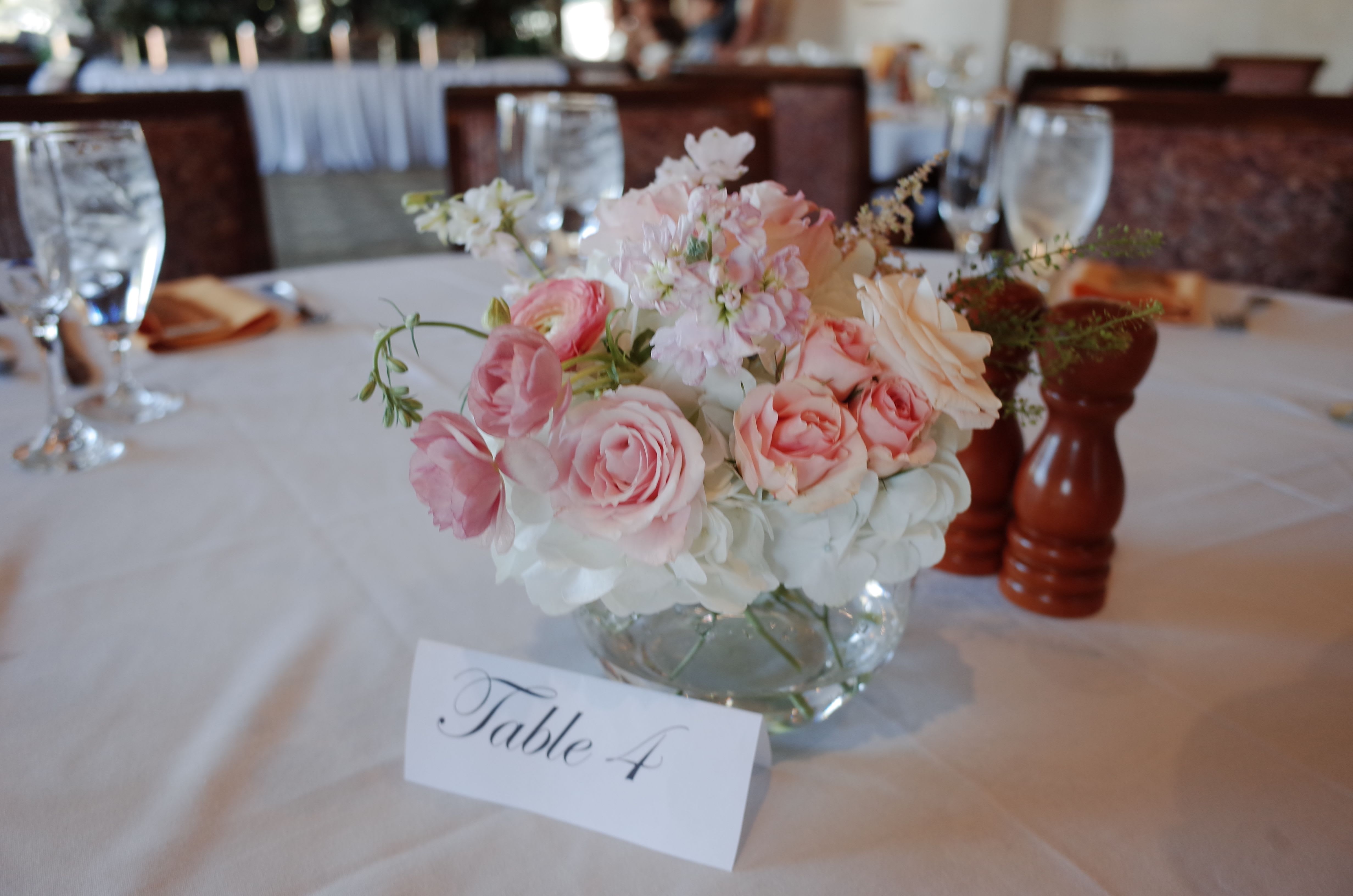 Pink and white floral centerpiece in a glass bowl on a table