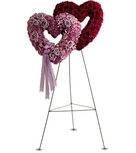 Two heart-shaped floral wreaths on stands, one with a ribbon tail
