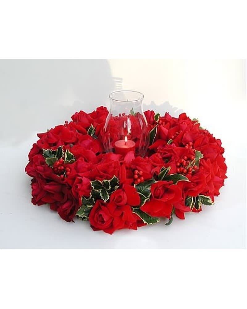 Round wreath of red roses with holly and a glass candle holder in the center