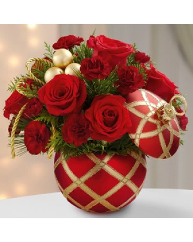 Red roses and carnations arranged in a red ornament-shaped container with gold accents and baubles.