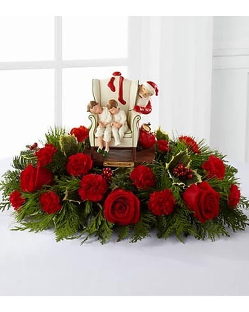 Holiday centerpiece of red roses and carnations with Santa and children figurine in the middle