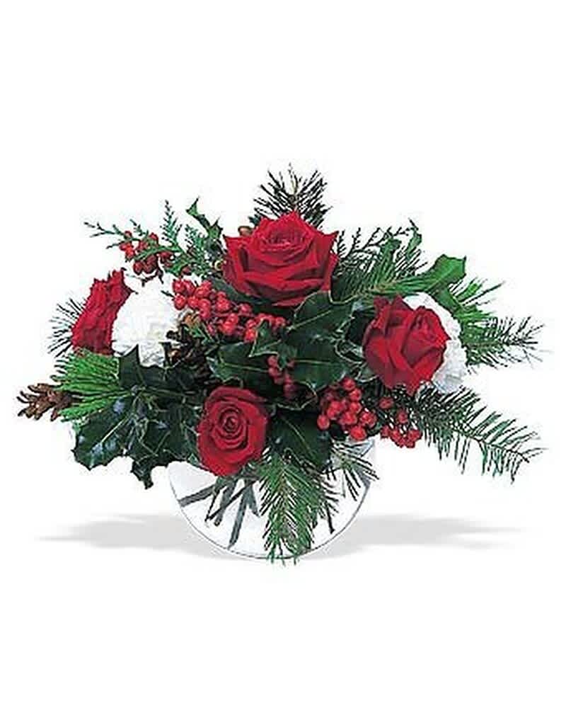 Low arrangement of red roses, white flowers, and red berries in a clear glass bowl