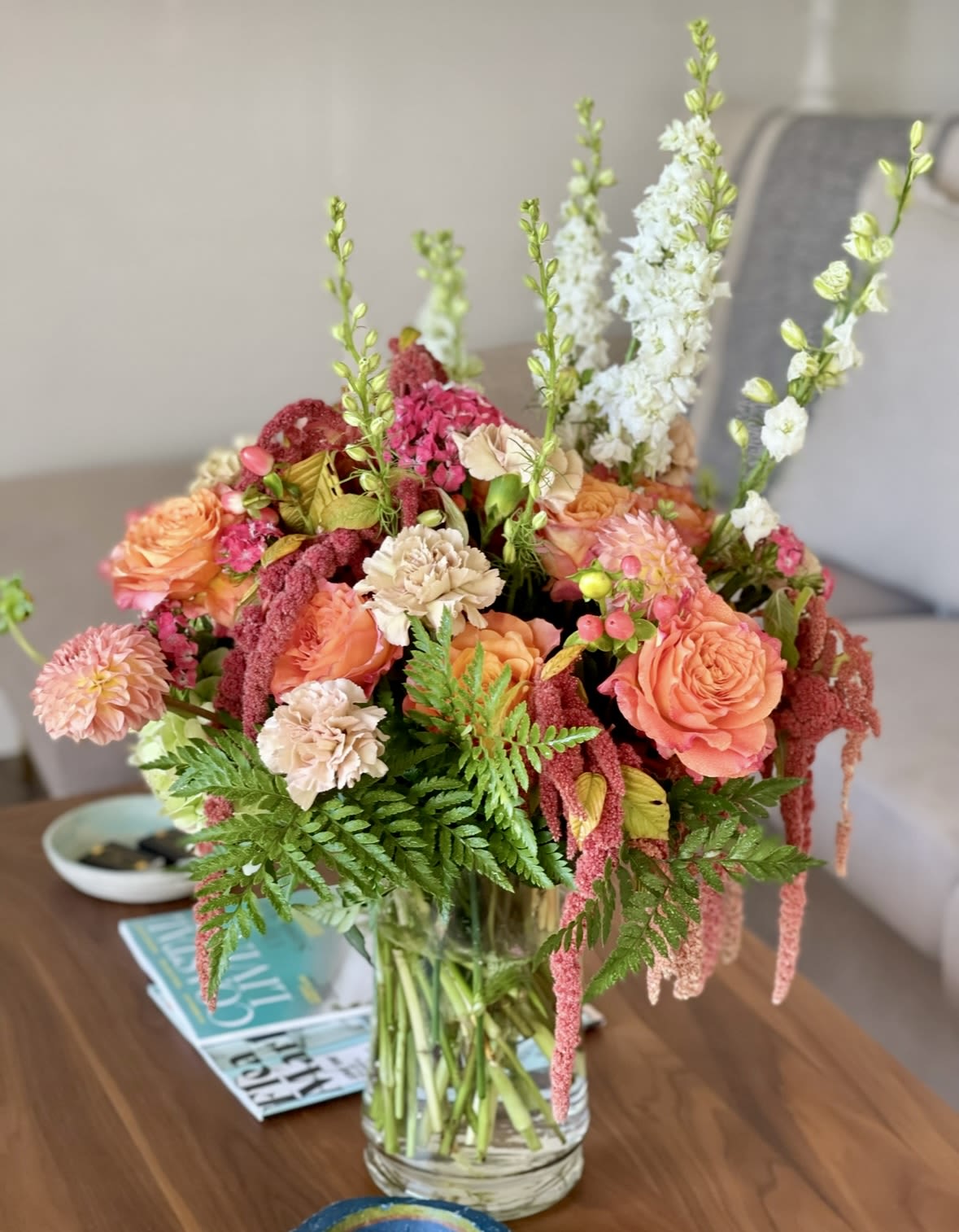 Mixed bouquet of peach and pink flowers in a clear glass vase