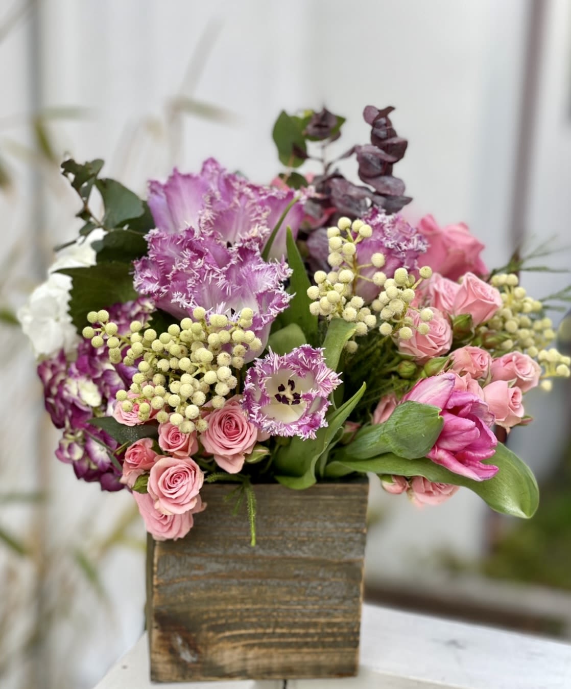 Pink and purple floral arrangement in a wooden box