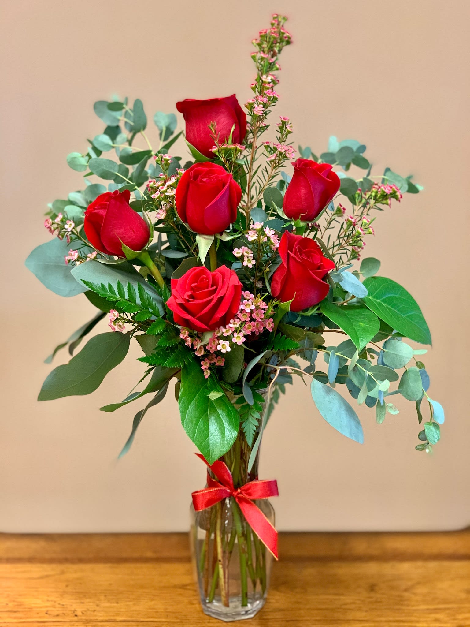 Red roses in a clear glass vase with pink filler flowers