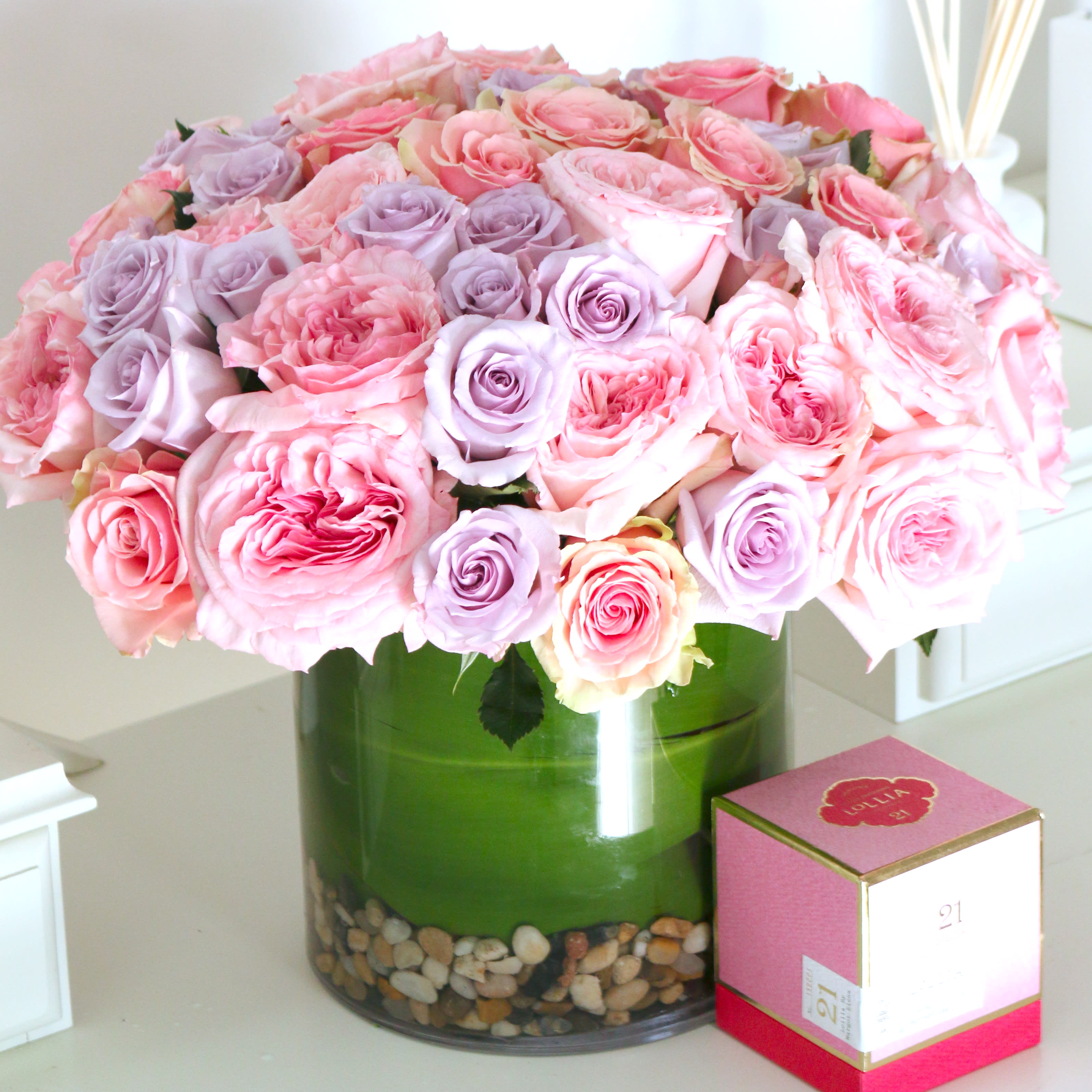 Pink and lavender roses arranged in a green glass vase