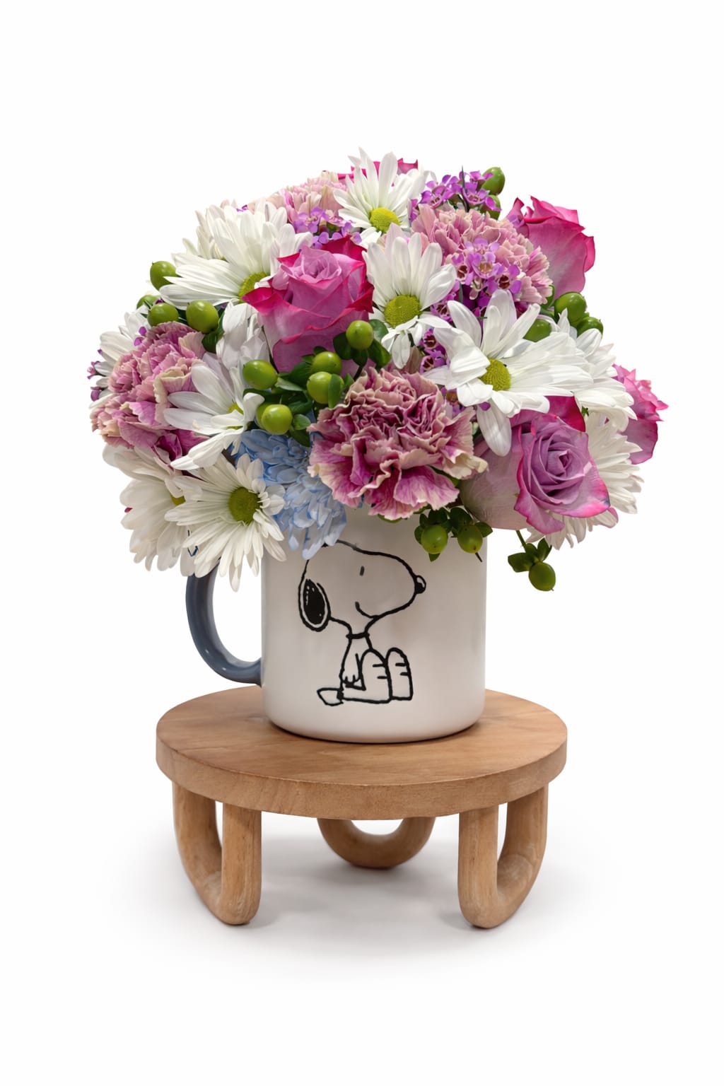 Snoopy’s Sweet Surprise - A playful and heartwarming floral arrangement designed in a collectible Snoopy keepsake mug.Featuring lavender roses, soft carnations, cheerful, white daisies, blue Blooms , green hypericum berries, fresh seasonal accent. This design is perfect for birthdays celebration and get well wishes or sending a smile just because.
