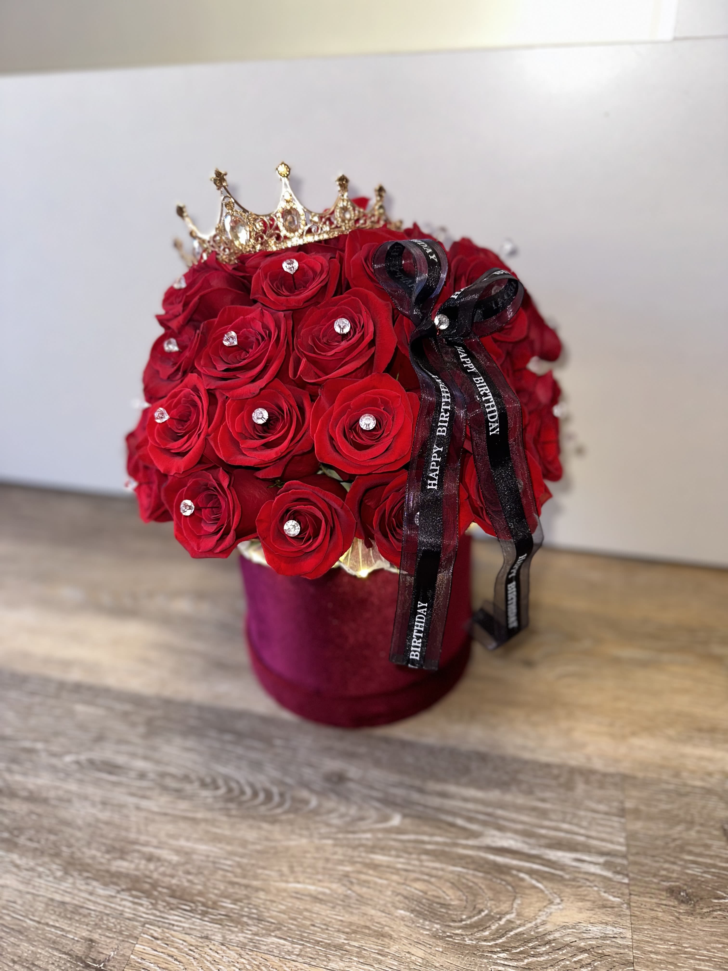 Red rose arrangement in a velvet box with a crown and birthday ribbon
