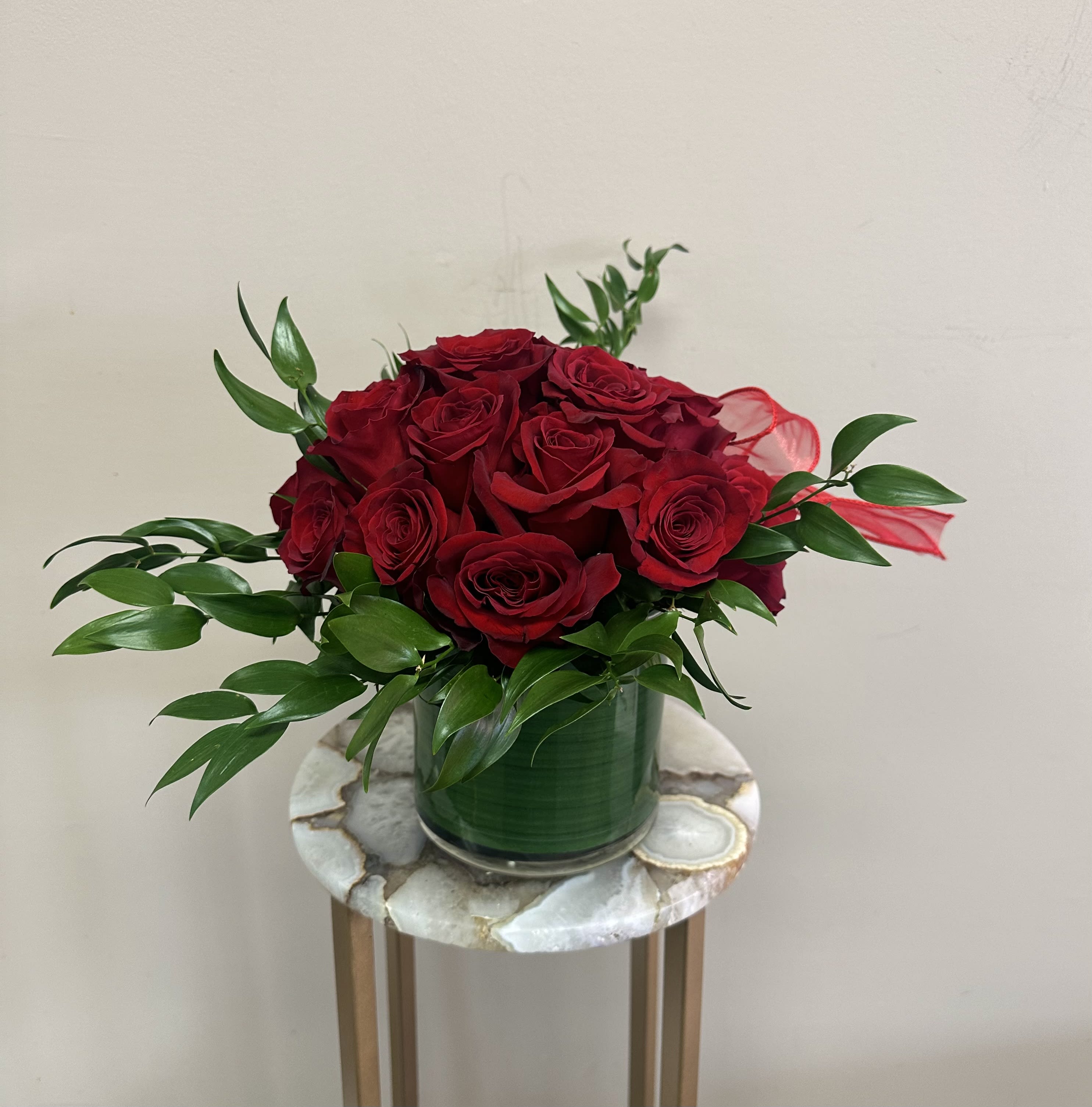 Red roses arranged in a green vase with glossy foliage