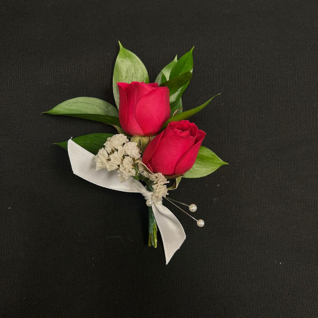 Two red rose boutonnieres with white ribbon and pearl accents
