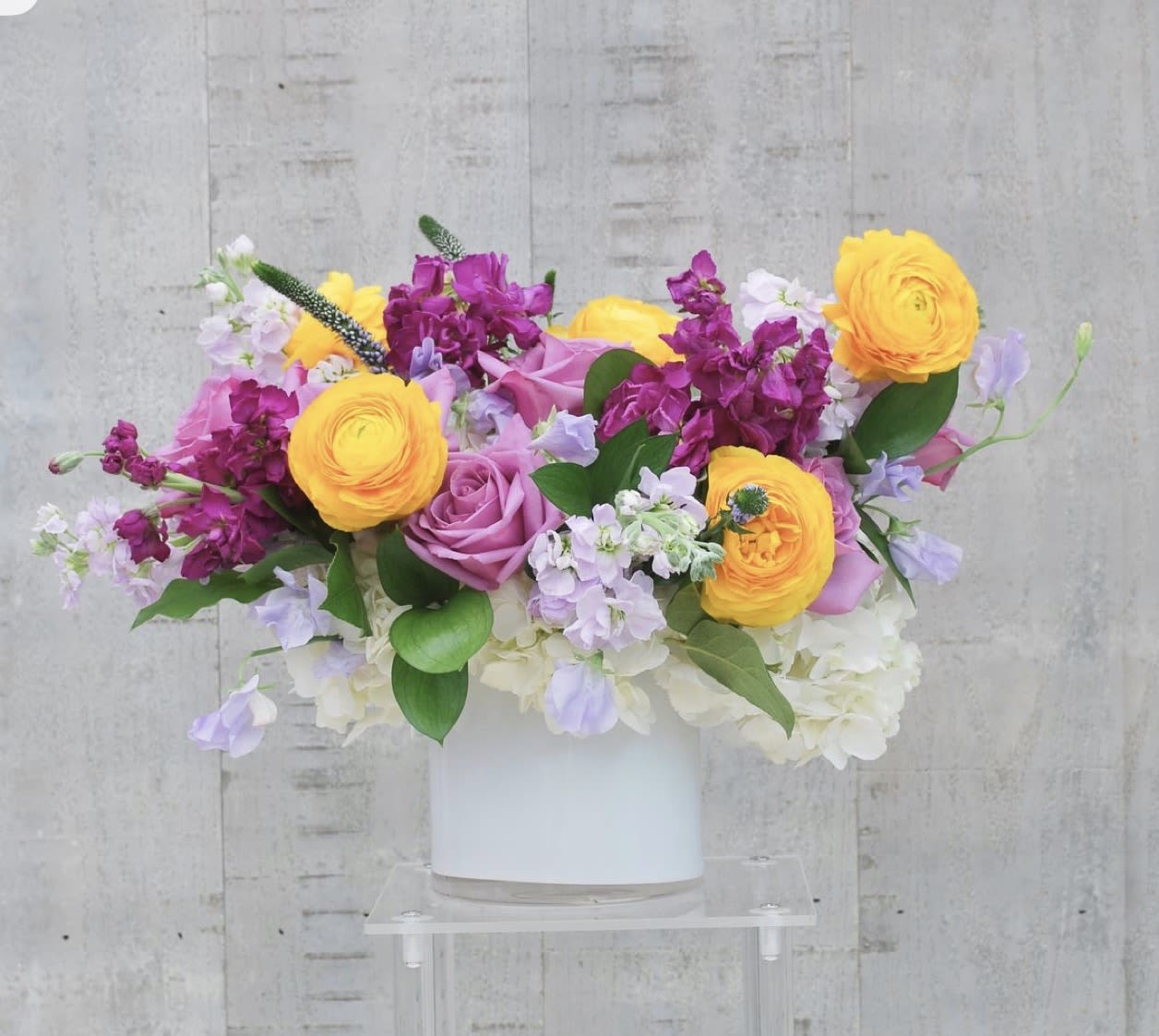 Bouquet of yellow, pink, and lavender flowers in a white vase