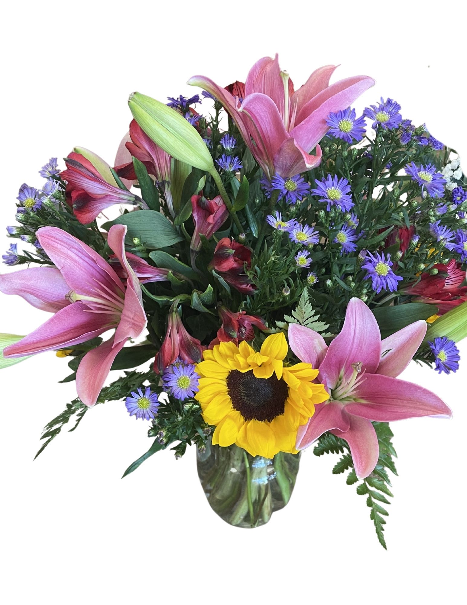 Bouquet of pink lilies, purple daisies, and a sunflower in a glass vase