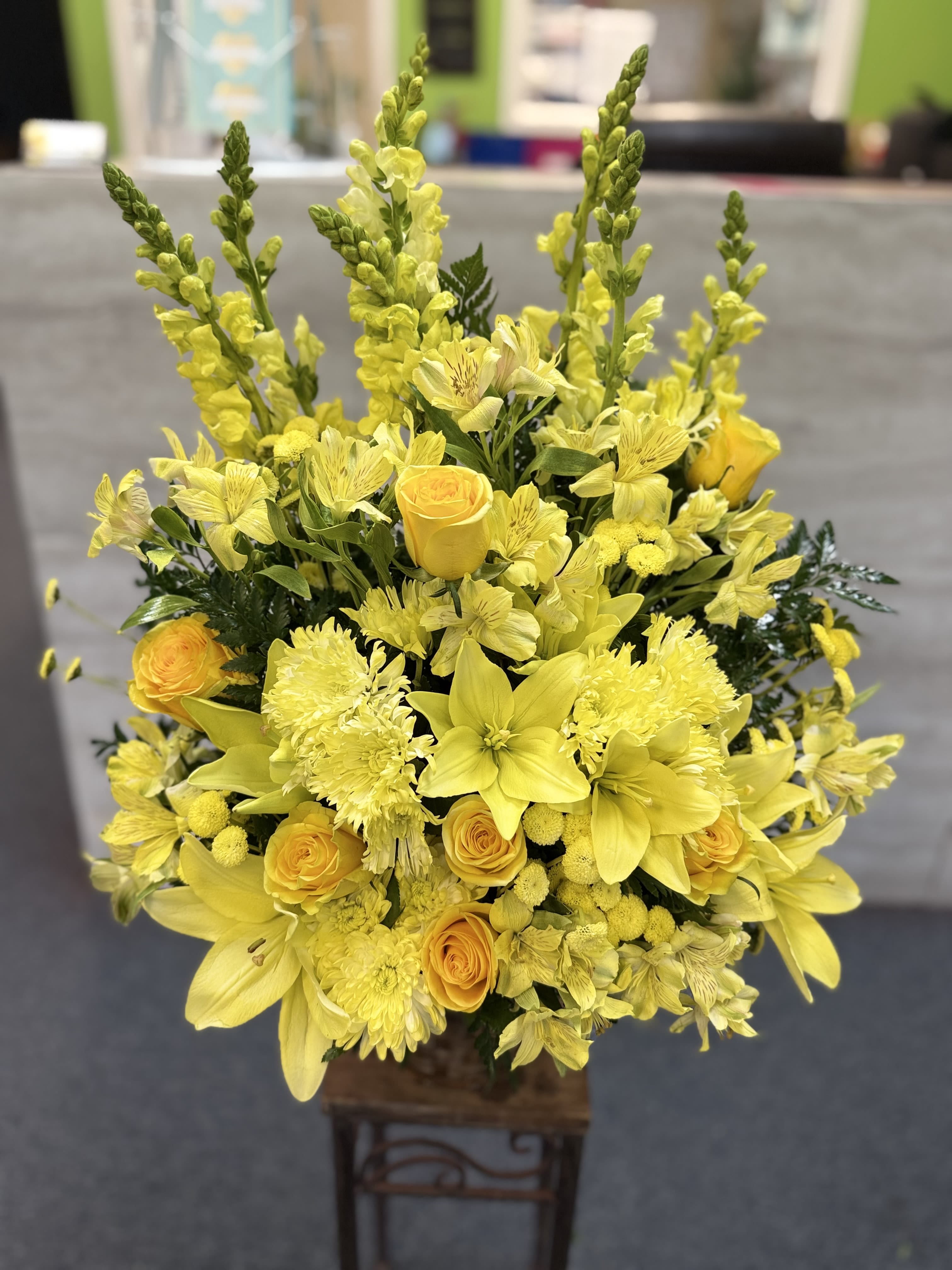 Sunny Memory - (ONE-SIDED) This cheerful arrangement features vibrant yellow roses, lilies, chrysanthemums, and alstroemeria, accented with bright snapdragons and fresh greenery. Full of warmth and energy, it’s a sunny bouquet that radiates happiness and positivity. 