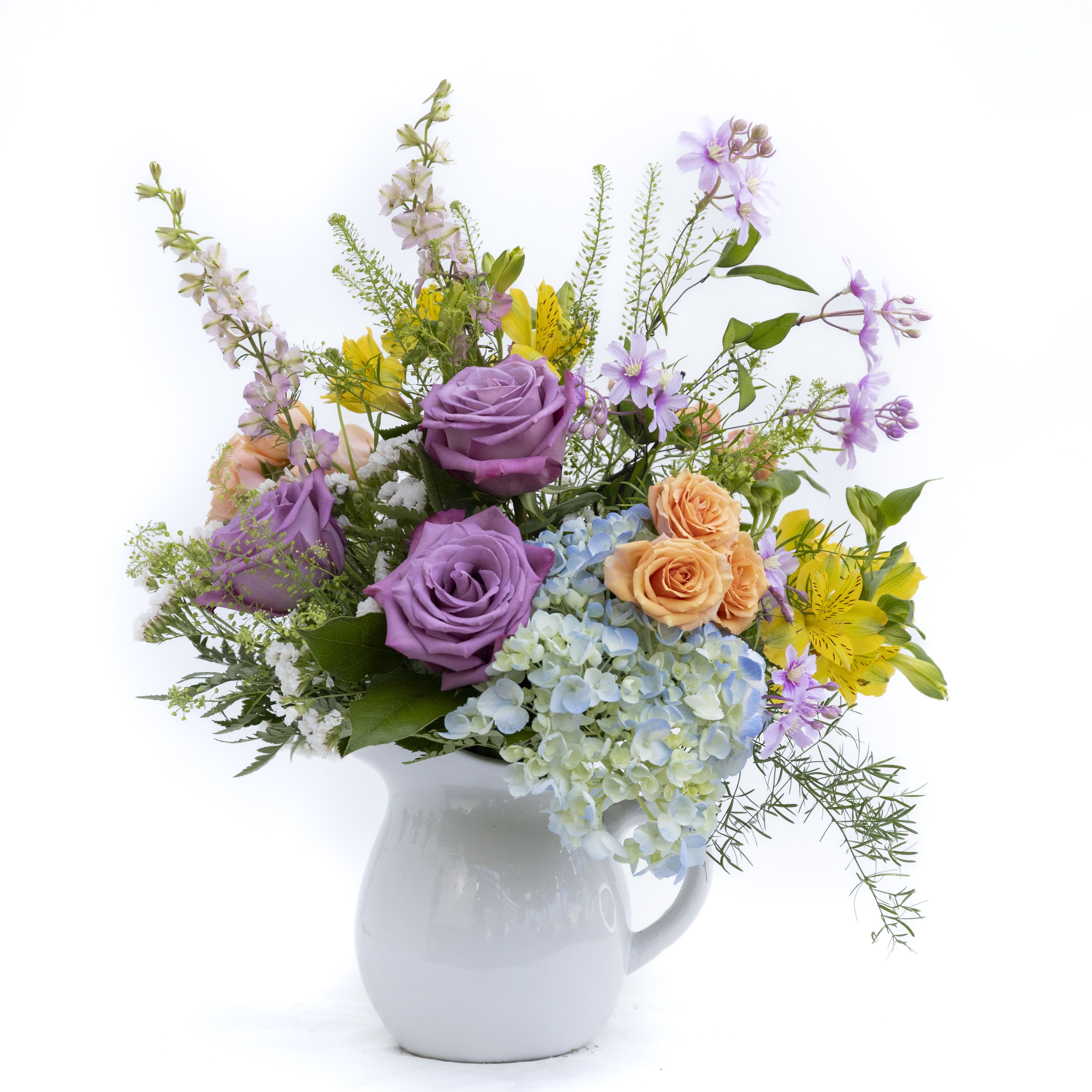 The Charlotte - The Charlotte with have you dreaming of summer days. A classic ceramic pitcher is overflowing with classic blue hydrangea, summery peach spray roses, rich purple roses and vibrant yellow alstroemeria. Airy elements like pink larkspur, springrye and little purple flowers with have feeling a Syracuse summer. Once you enjoy your flowers you will be left with a perfect white pitcher to fill with your favorite summer drink or those hydrangea you cut from Moms yard.  Delivery to Syracuse, North Syracuse, East Syracuse, Dewitt, Manlius, Jamesville, Fayetteville, Camillus, Marcellus, Minor, Mattydale, Liverpool