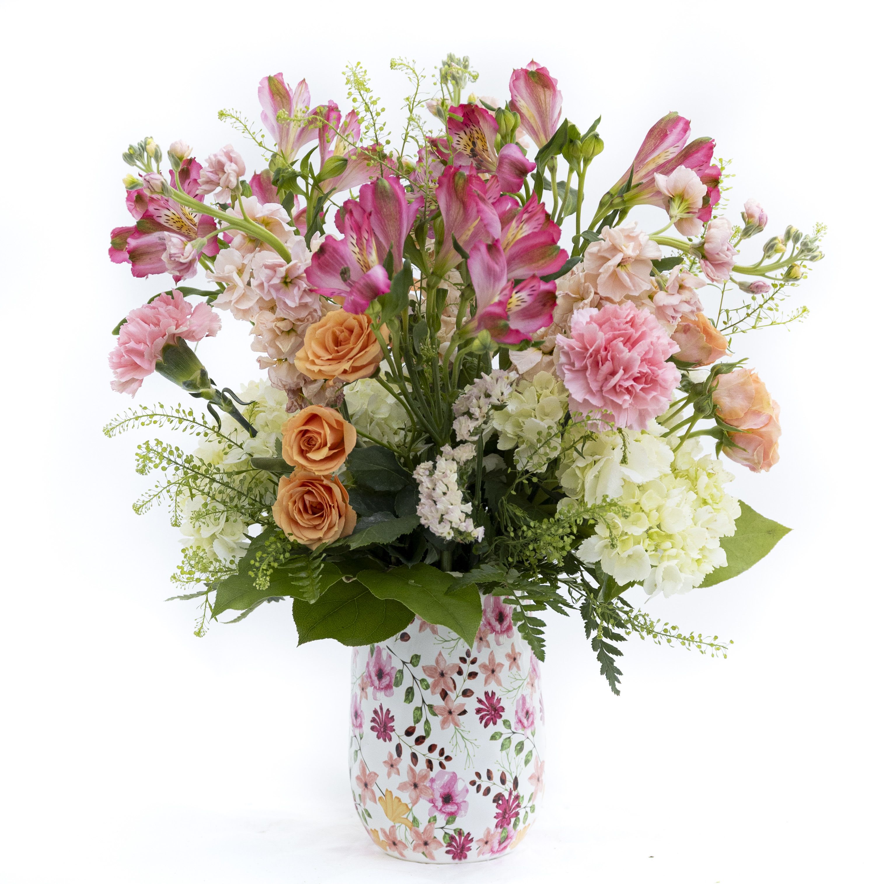 The Layla - A soft, romantic floral arrangement that blends delicate pinks, warm peach tones, and fresh greenery into an effortlessly elegant display. Featuring a lush mix of roses, carnations, and seasonal blooms, this arrangement brings a gentle charm and natural beauty to any space. Designed in a floral-patterned vase that echoes the bouquet’s palette, it’s perfect for celebrating special moments or adding a touch of graceful warmth to everyday life. Delivery to Syracuse, North Syracuse, East Syracuse, Dewitt, Manlius, Jamesville, Fayetteville, Camillus, Marcellus, Minor, Mattydale, Liverpool