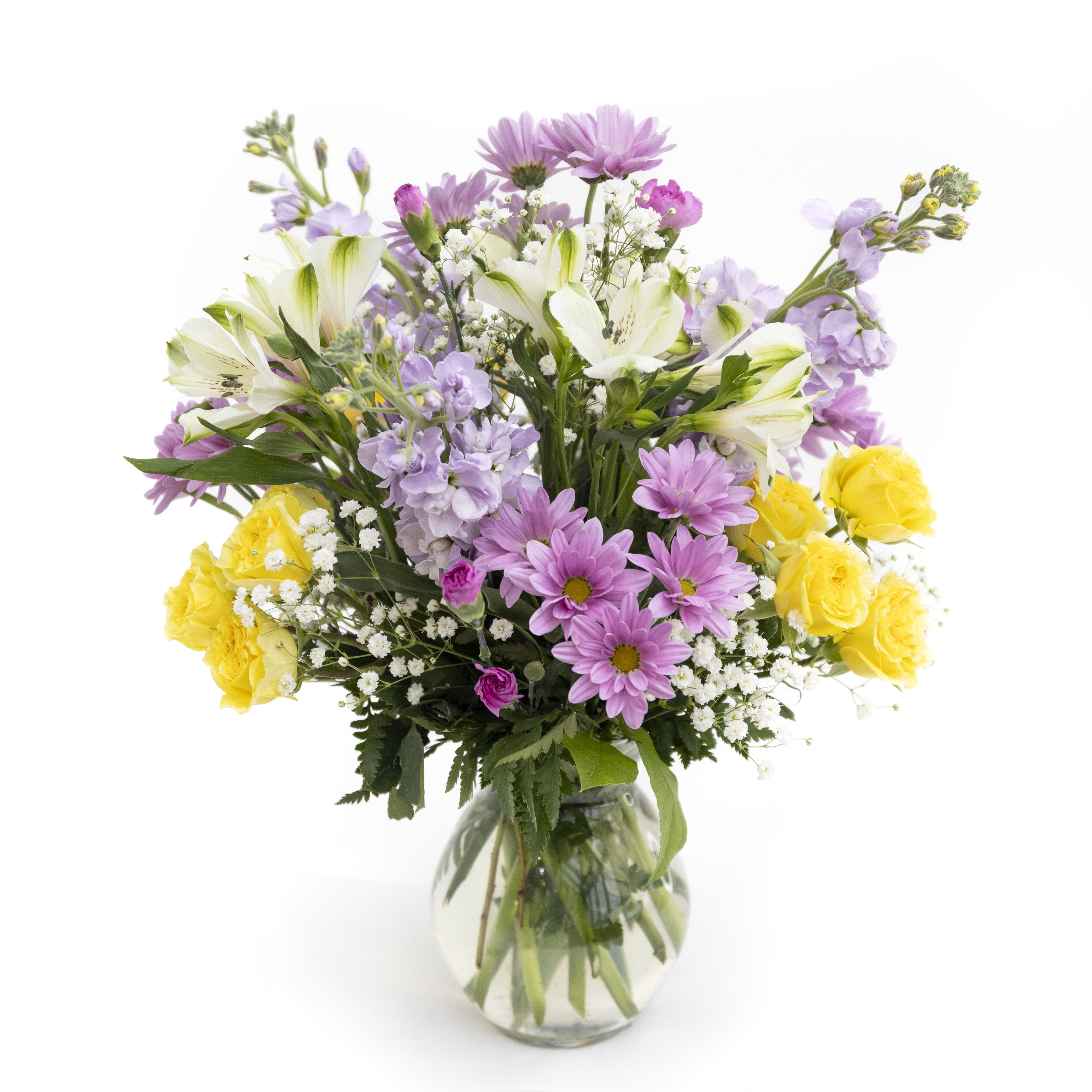 Garden Glow - Garden Glow is a cheerful, garden-inspired arrangement bursting with fresh spring color. Sunny yellow roses bring warmth and happiness, while soft lavender stock, pastel daisies, and elegant white alstroemeria add layers of texture and charm. Finished with delicate baby’s breath and lush greenery, this bouquet feels light, joyful, and naturally abundant. Designed in a clear glass vase, Garden Glow is perfect for celebrating new beginnings, sharing gratitude, or bringing a touch of sunshine indoors. Delivery to Syracuse, North Syracuse, East Syracuse, Dewitt, Manlius, Jamesville, Fayetteville, Camillus, Marcellus, Minoa, Mattydale, Liverpool any space.