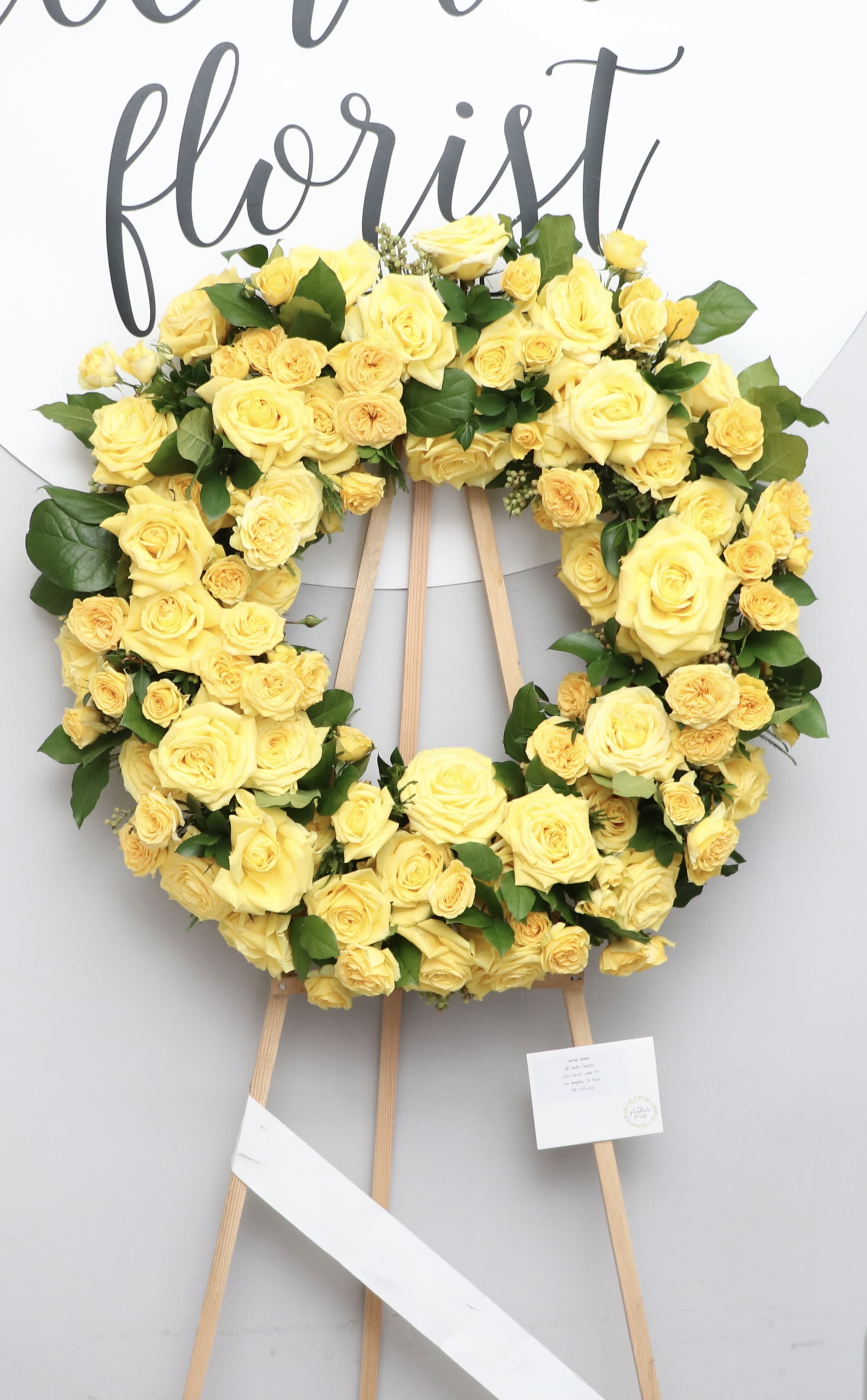Sunshine Farewell  - This sympathy wreath includes bright yellow roses and fluffy seasonal greens.  We include easel, printed banner and delivery (some fees may apply). An additional banner can be added for $15  Standard size is 30'', deluxe is 36'', and premium is 42''.