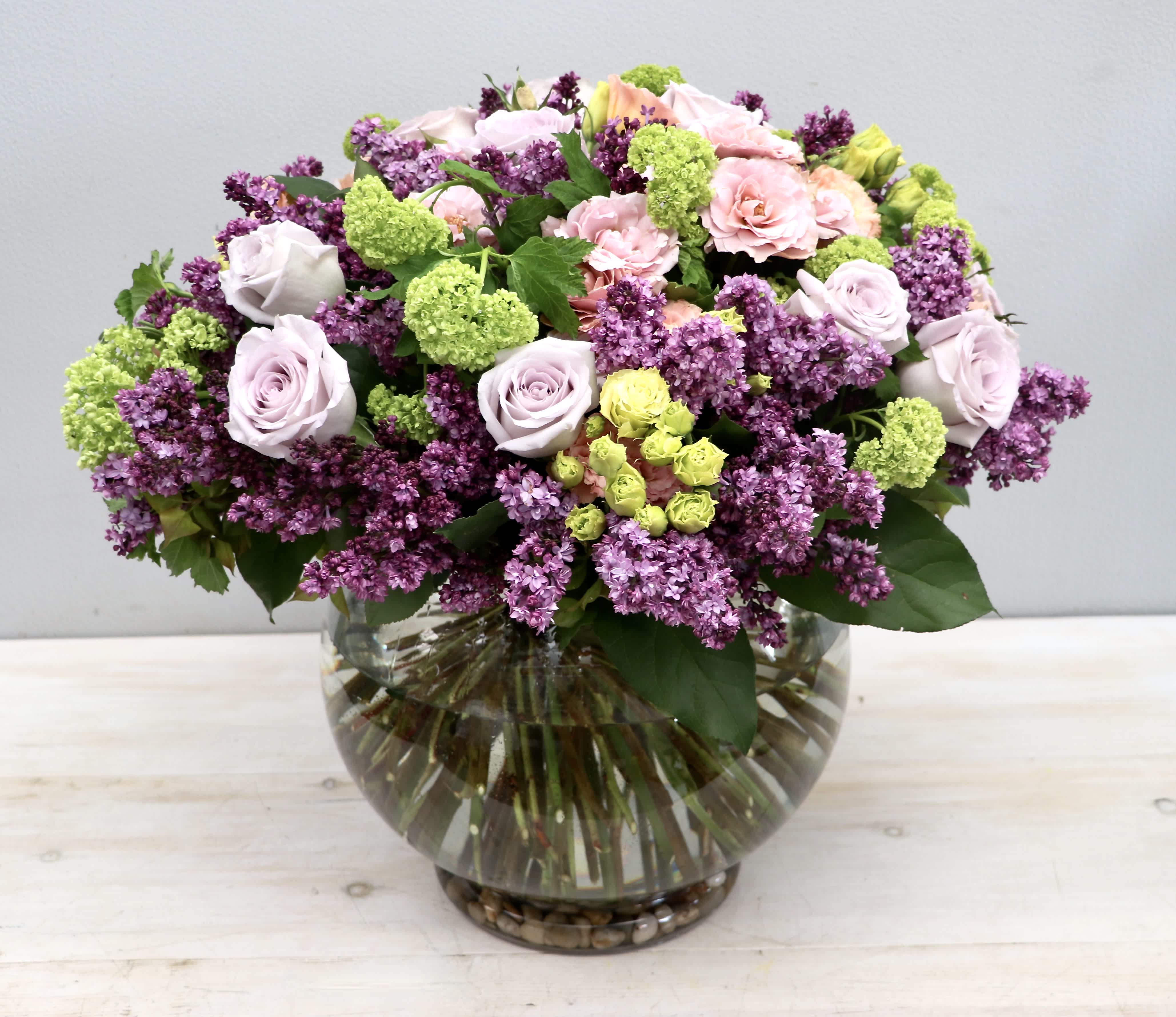 Bouquet of pink and purple flowers in a round glass vase